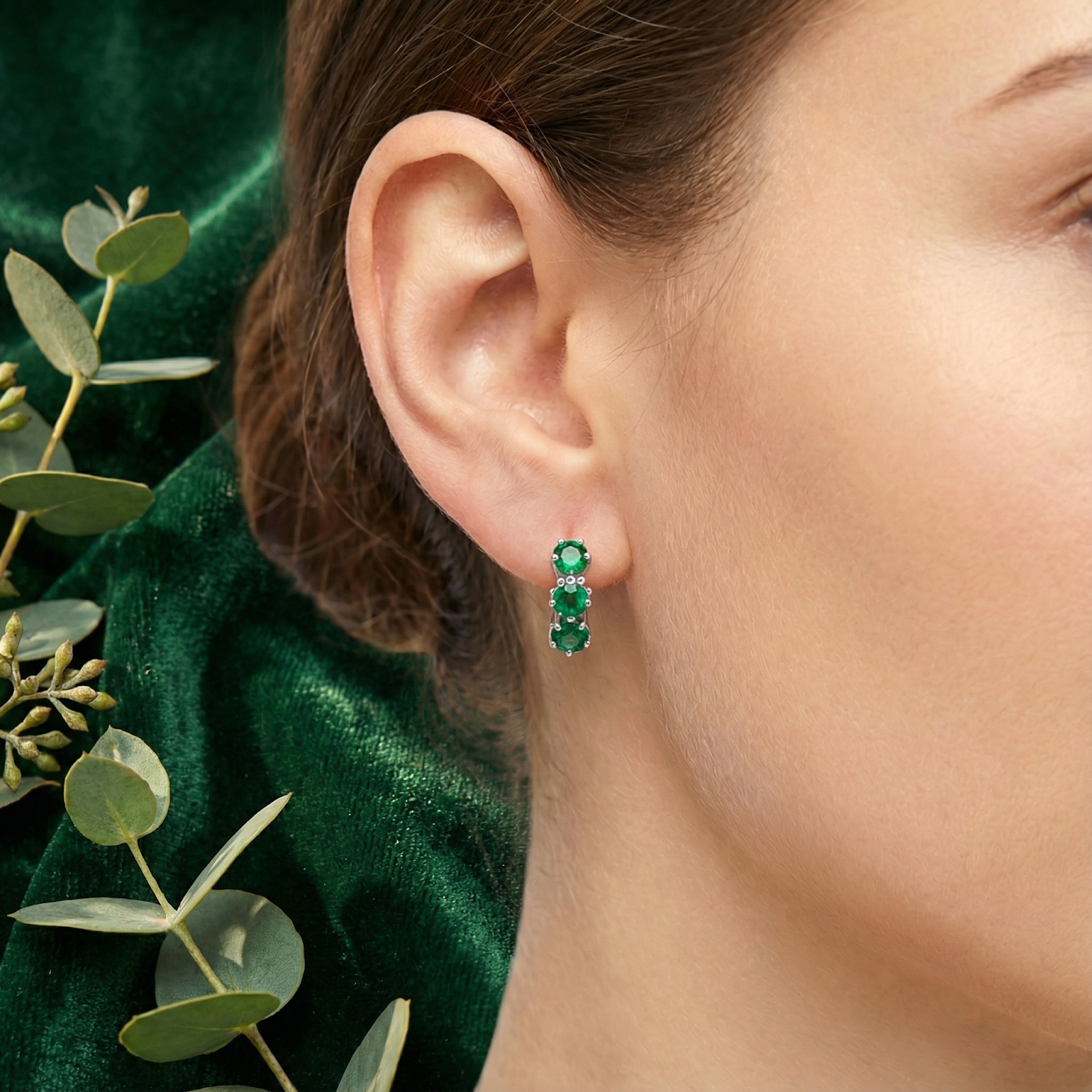 Woman wearing the triple star-cut simulated emerald sterling silver huggie earring on her ear.