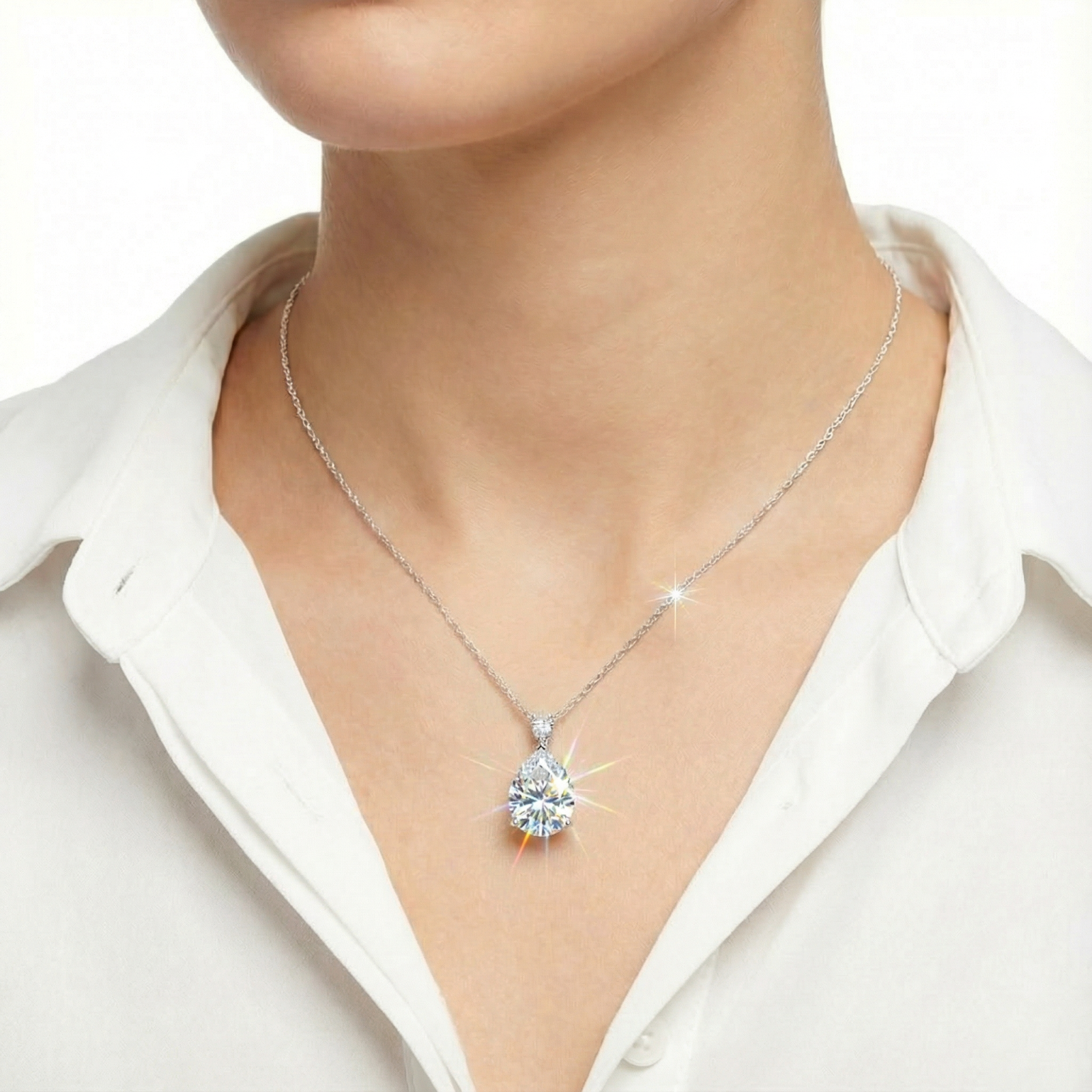 Front view of a model wearing the Sylphine pear-cut moissanite necklace in sterling silver over a white shirt.