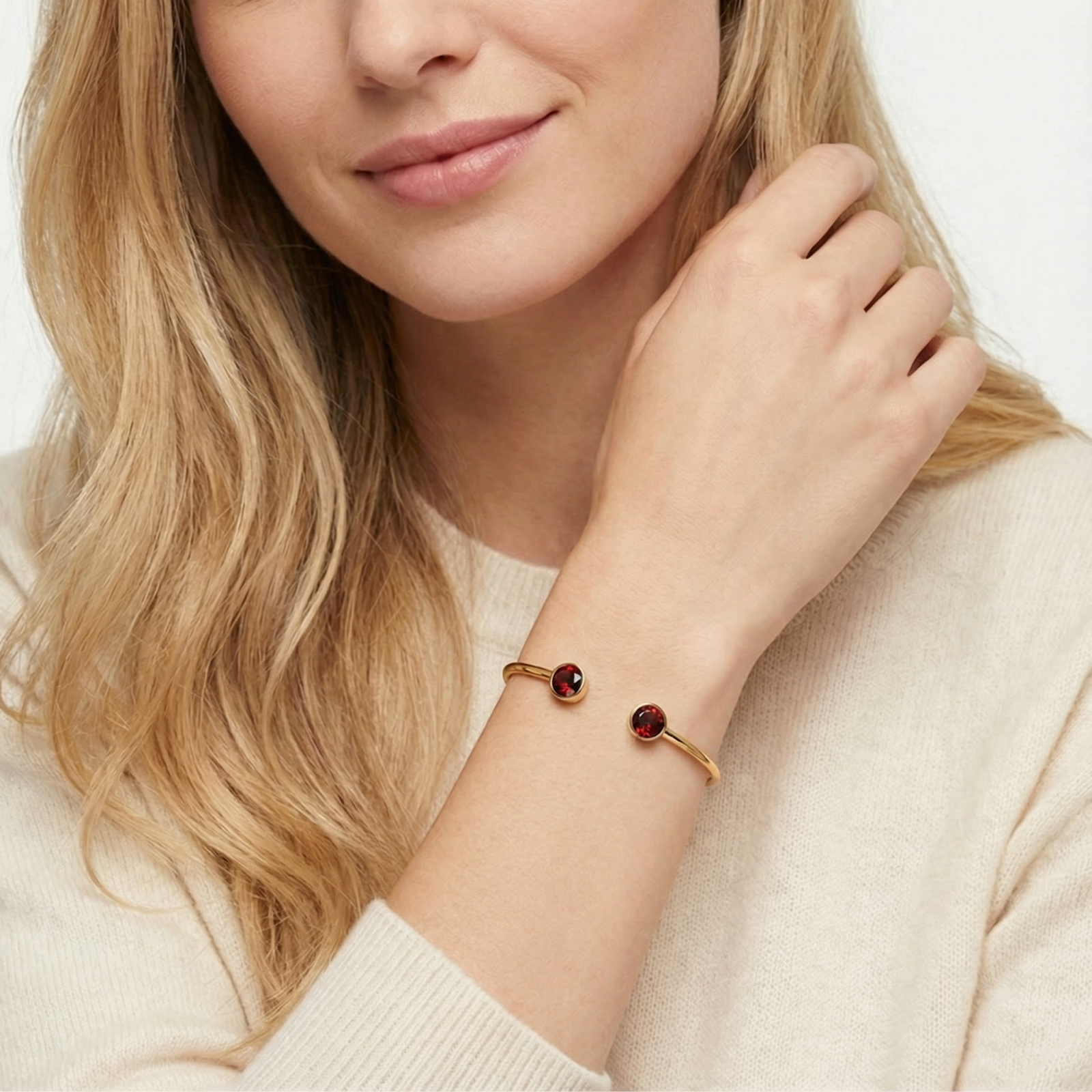 Gold ion-plated stainless steel cuff bracelet with red simulated garnets worn on a woman's wrist.
