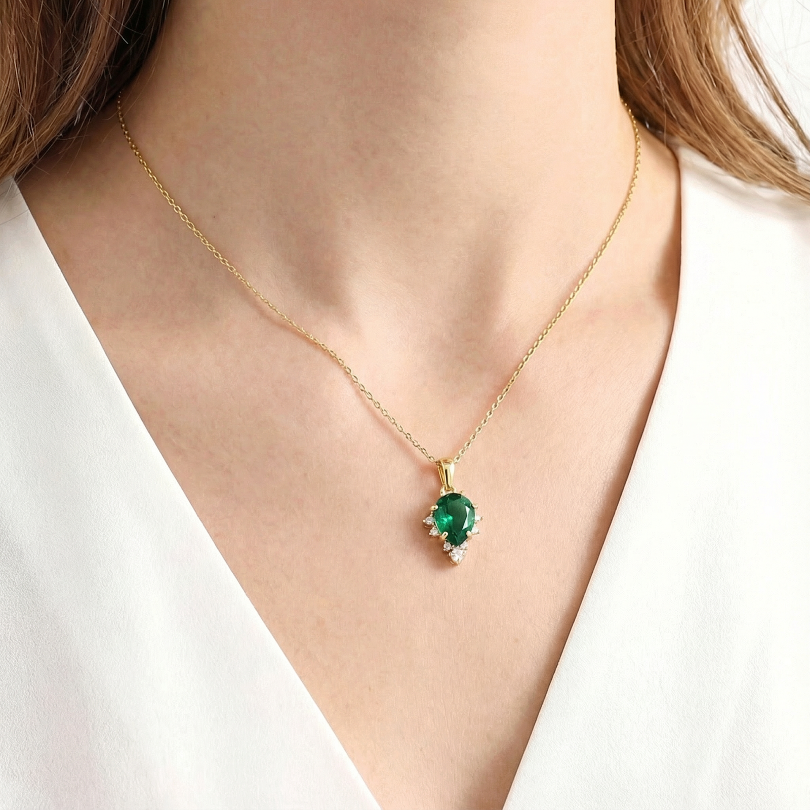 Woman wearing the Elaraea teardrop necklace with a pear-cut simulated emerald in 18K gold vermeil.