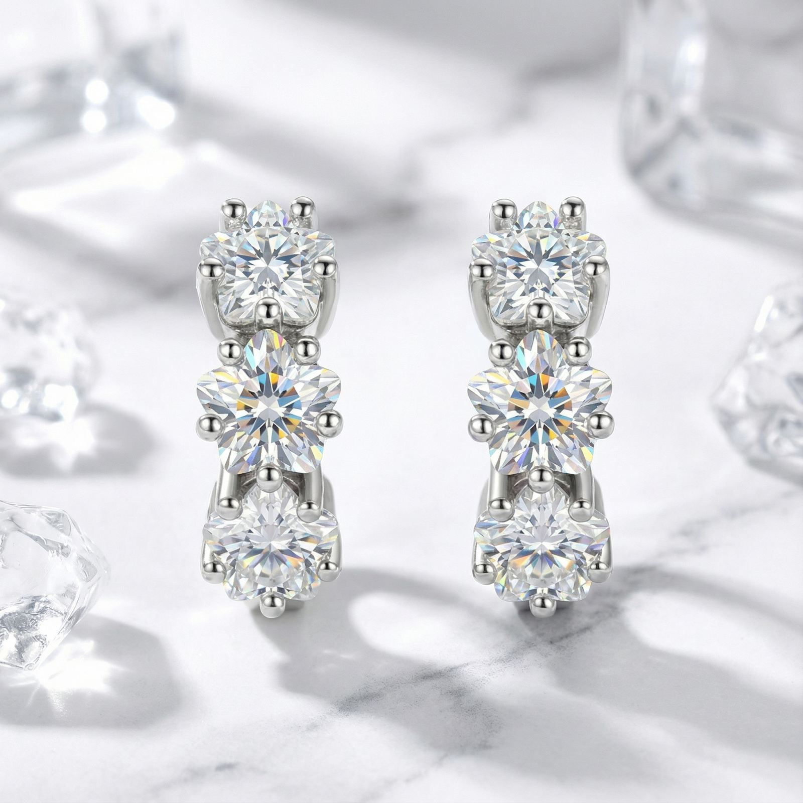 Front view of S925 sterling silver huggie earrings featuring three round-cut simulated diamonds on marble.