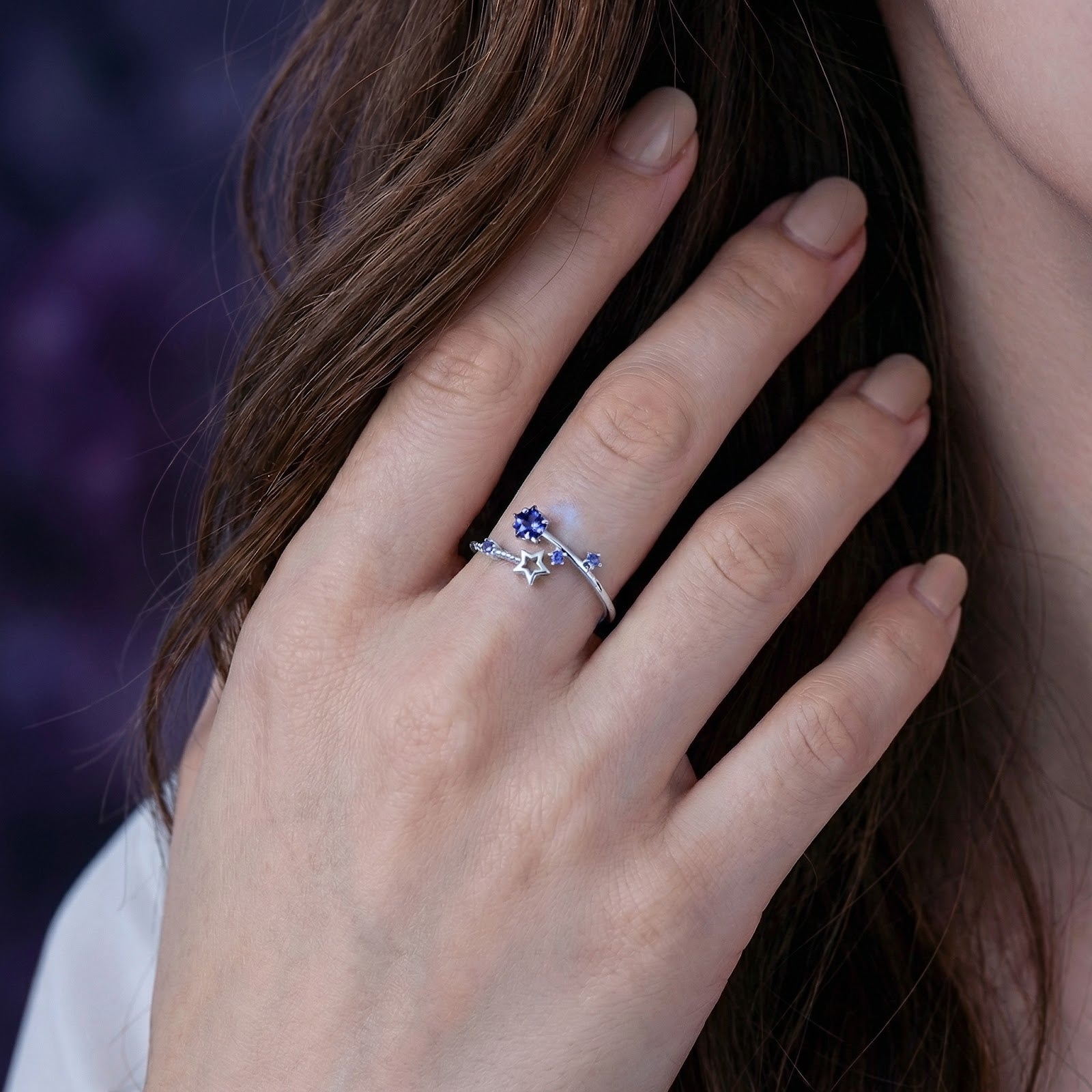 Sterling silver Nova Stellar ring with blue simulated tanzanite star accents worn on a woman's hand.