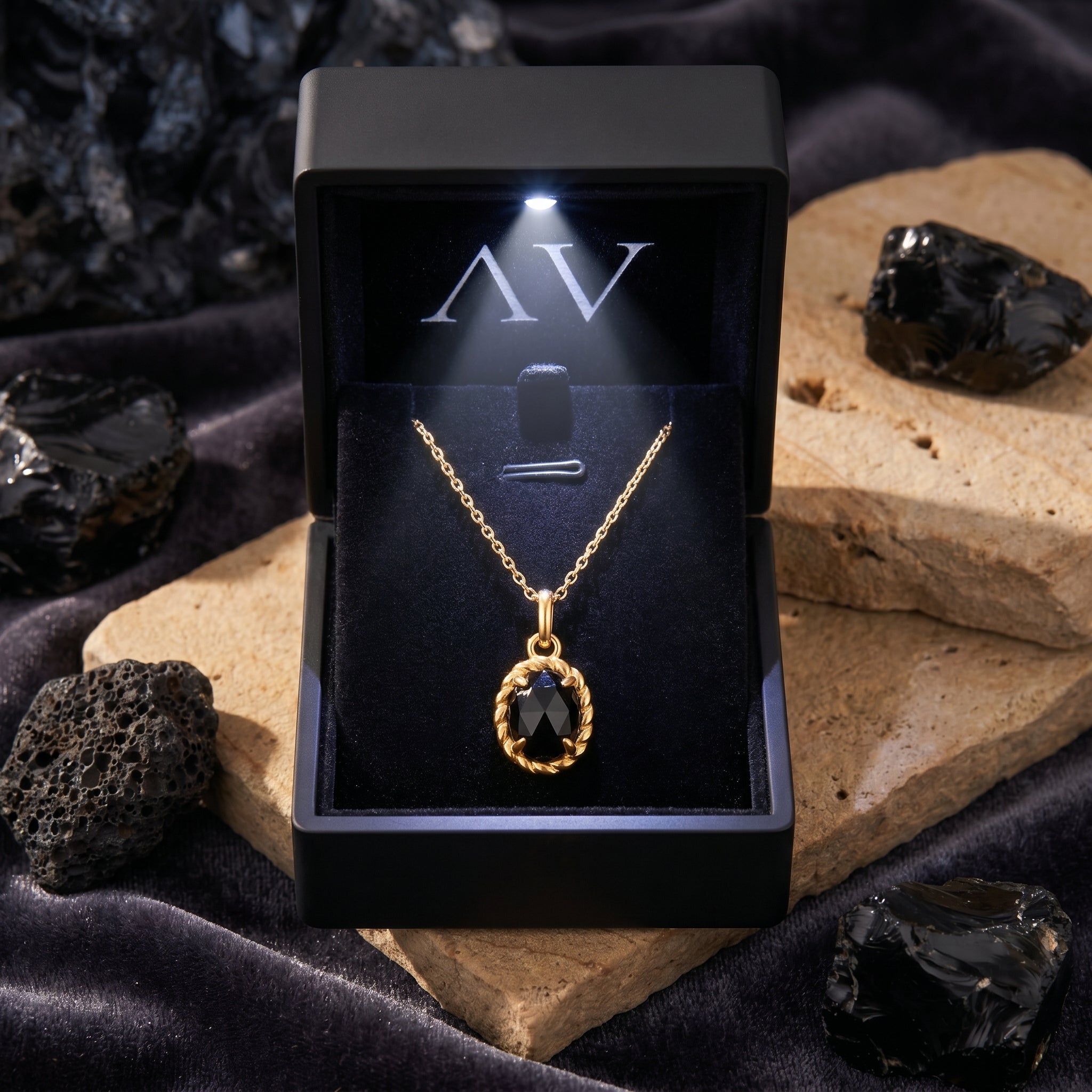 Yellow gold Raven Onyx Necklace presented in a black lighted jewelry box, showcasing the faceted oval black onyx stone.