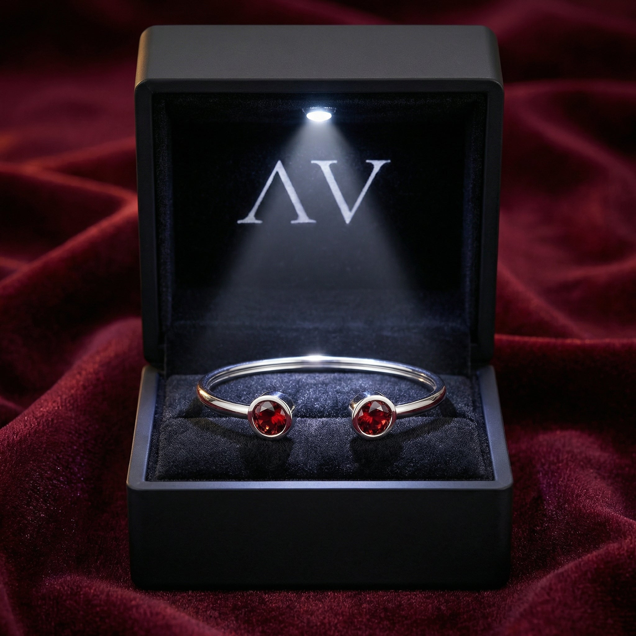 Stainless steel simulated garnet bracelet in a black LED-lit gift box on red velvet fabric.