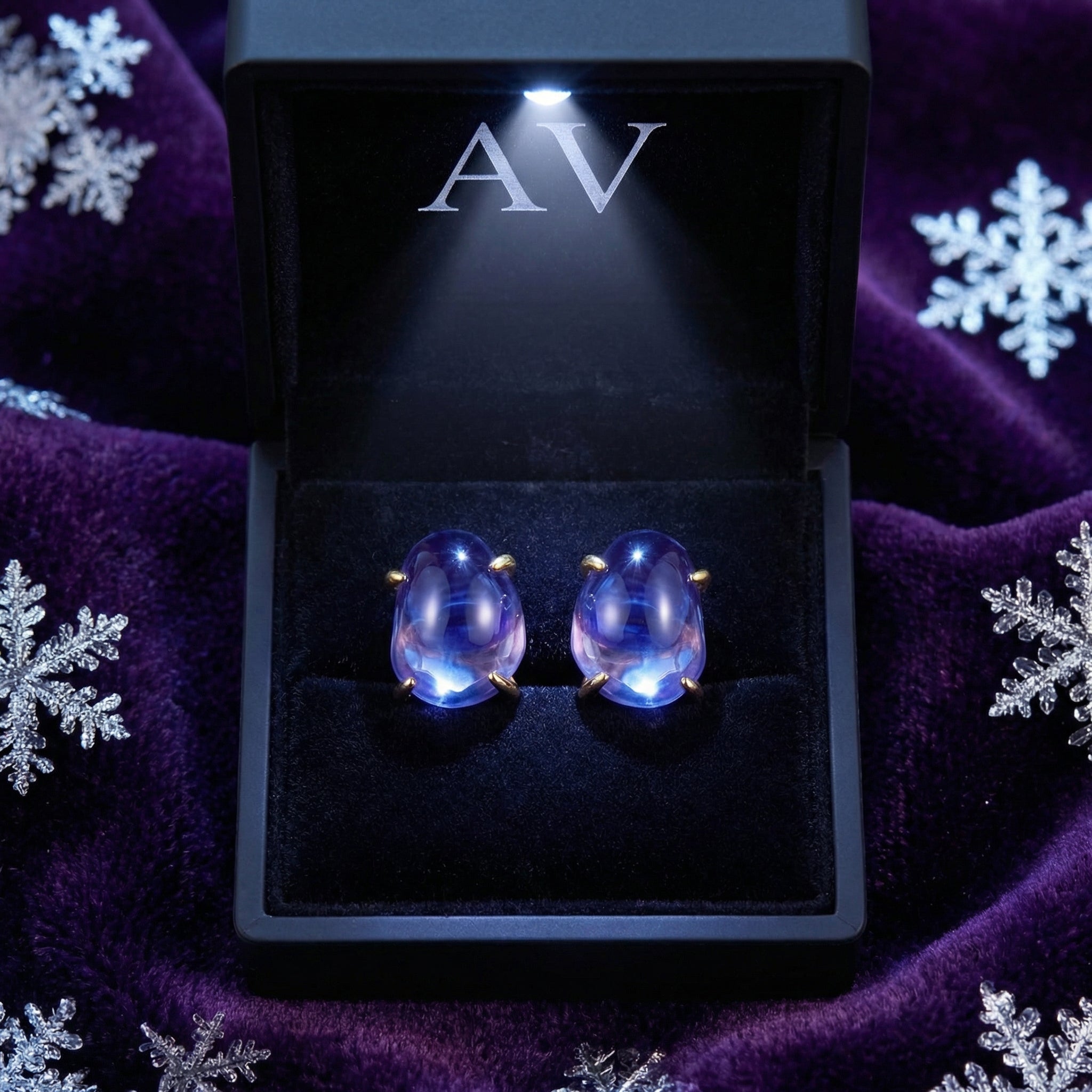 Alarina simulated tanzanite stud earrings in 18K gold vermeil inside a lighted black branded jewelry box.