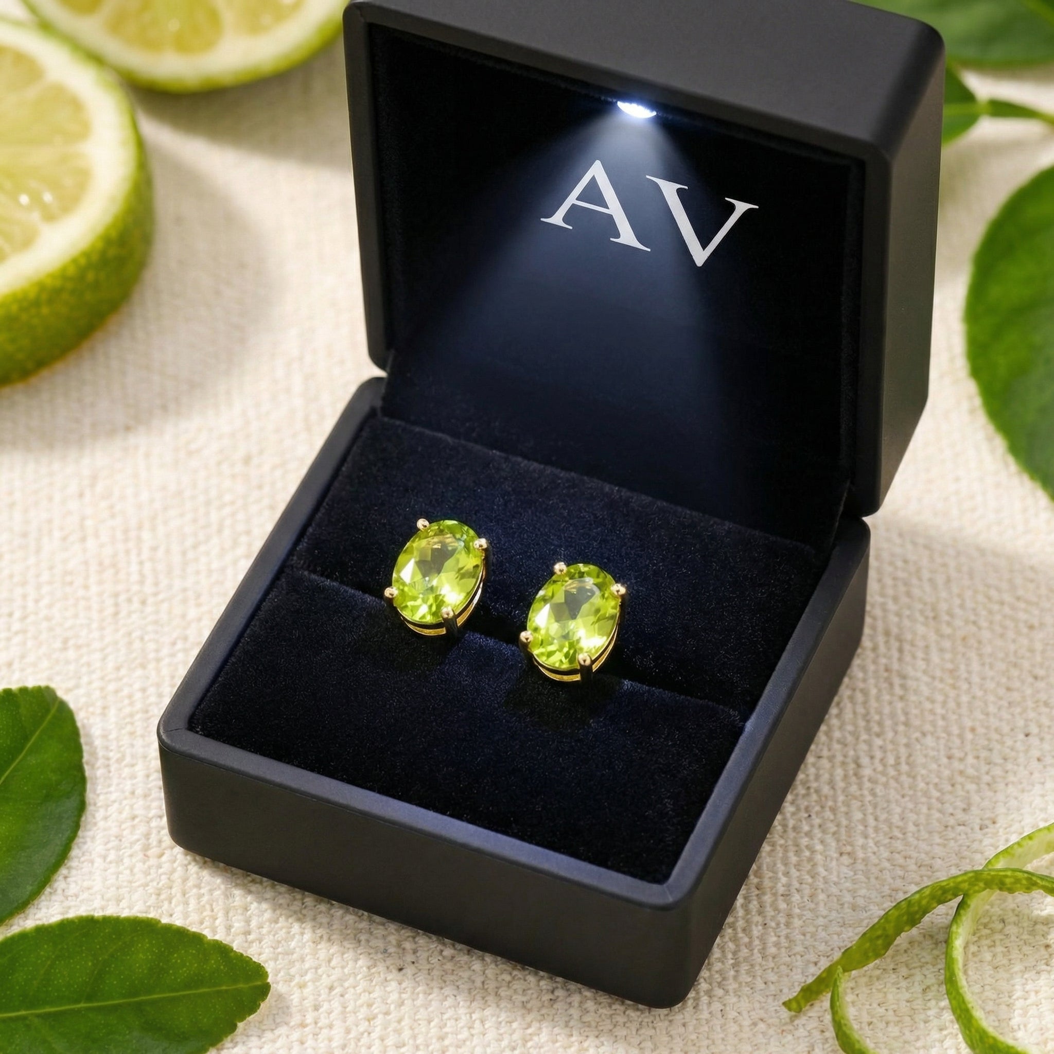 Oval-cut simulated peridot stud earrings in 18K gold vermeil presented in a black LED-lit jewelry box.