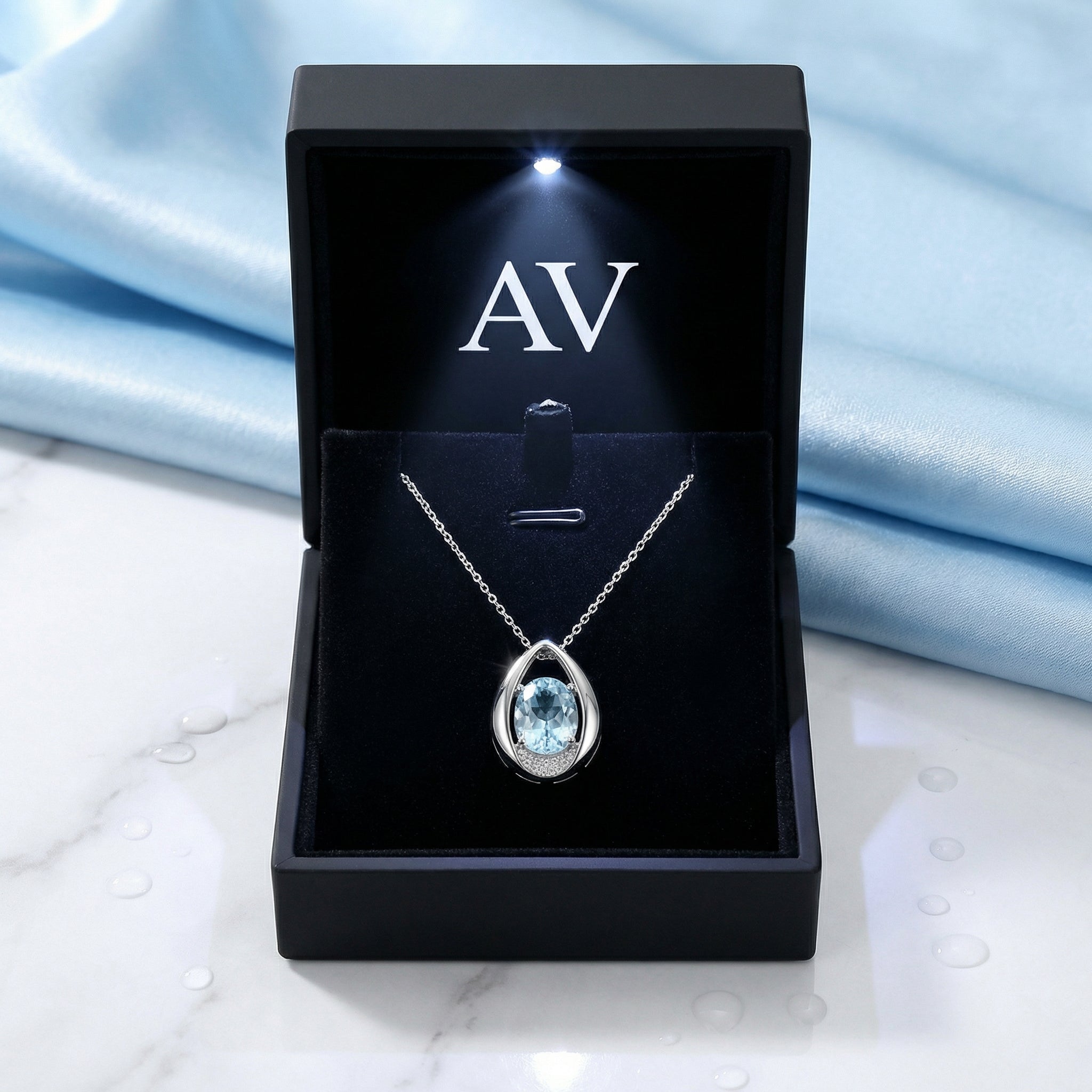 Front view of the blue simulated aquamarine teardrop necklace in a black branded presentation box with LED.