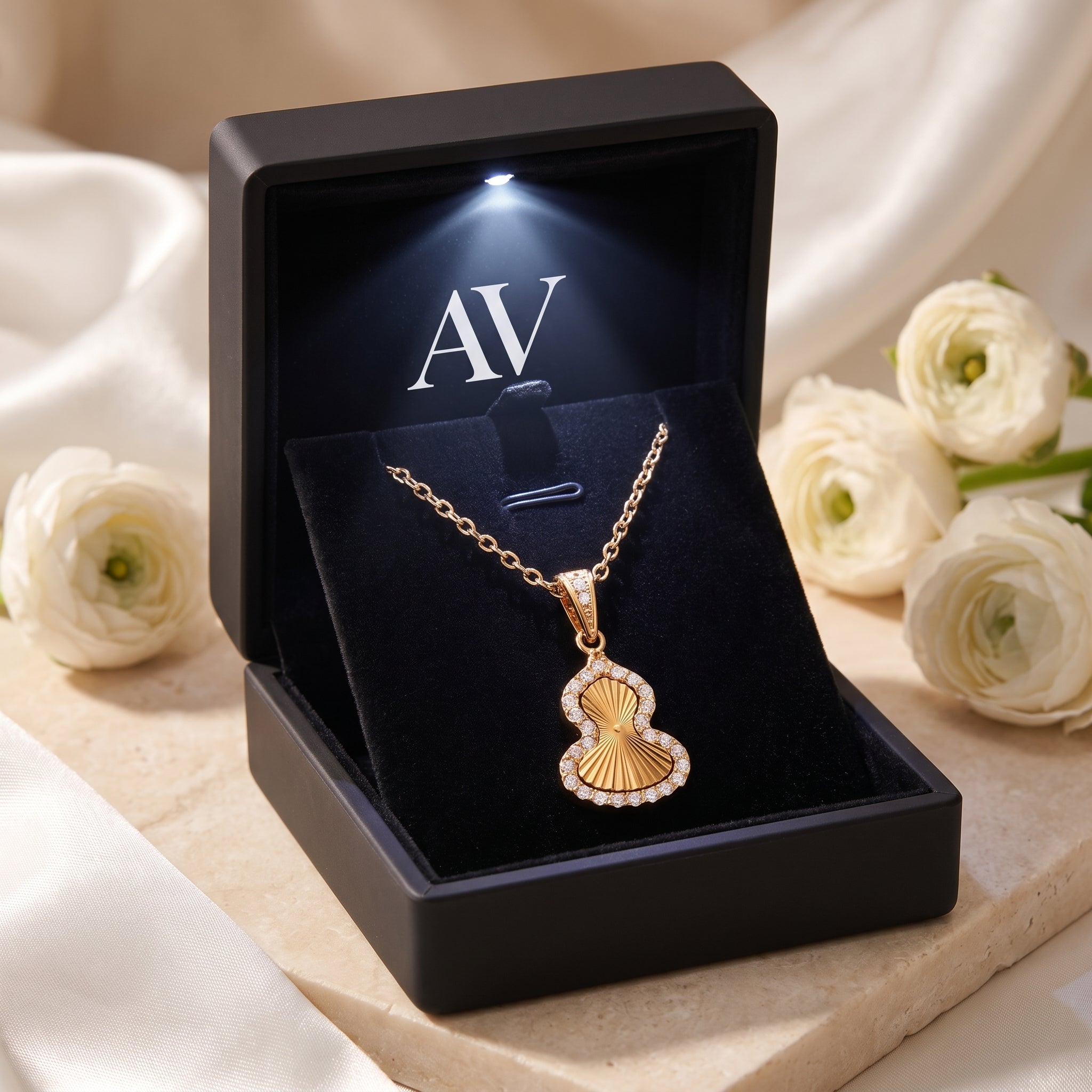 Gold gourd pendant necklace with cubic zirconia halo inside a lighted black jewelry box.