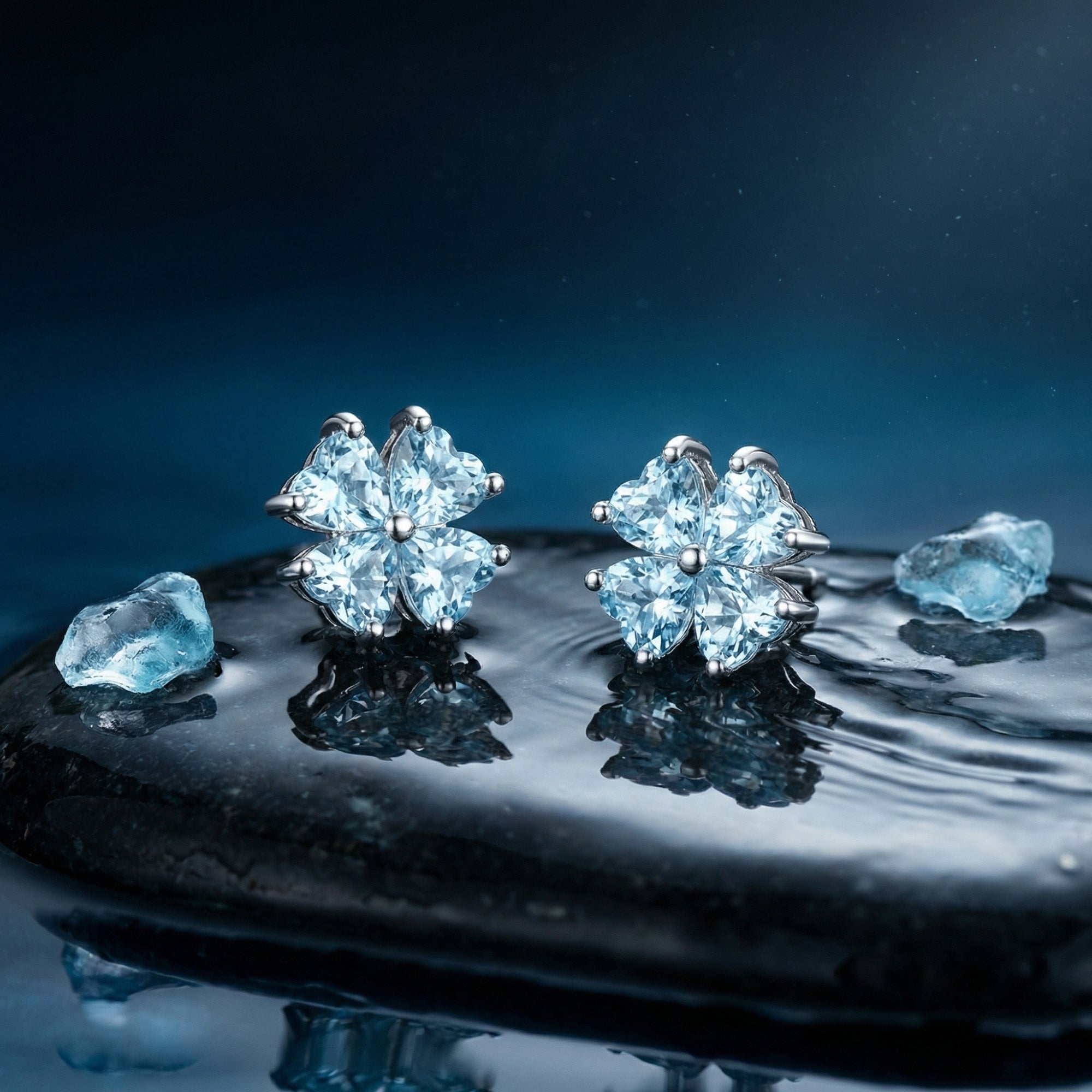 Front view of platinum clover stud earrings with heart-cut aquamarine stones on a wet dark stone.