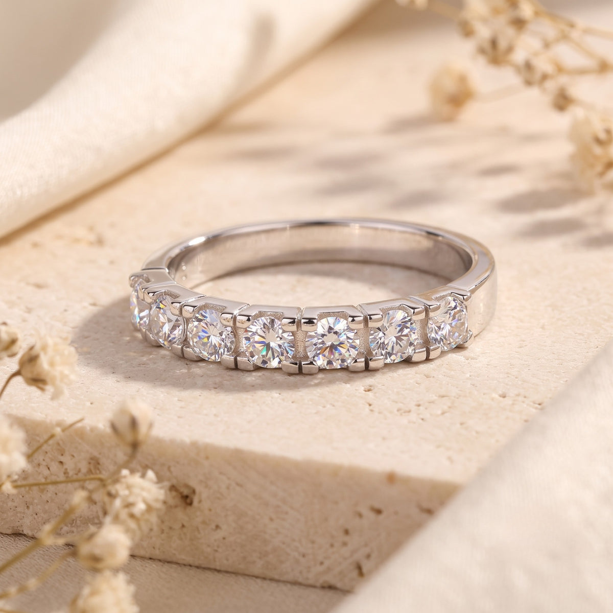 Front view of a silver ring with seven round clear stones in a shared-prong setting.