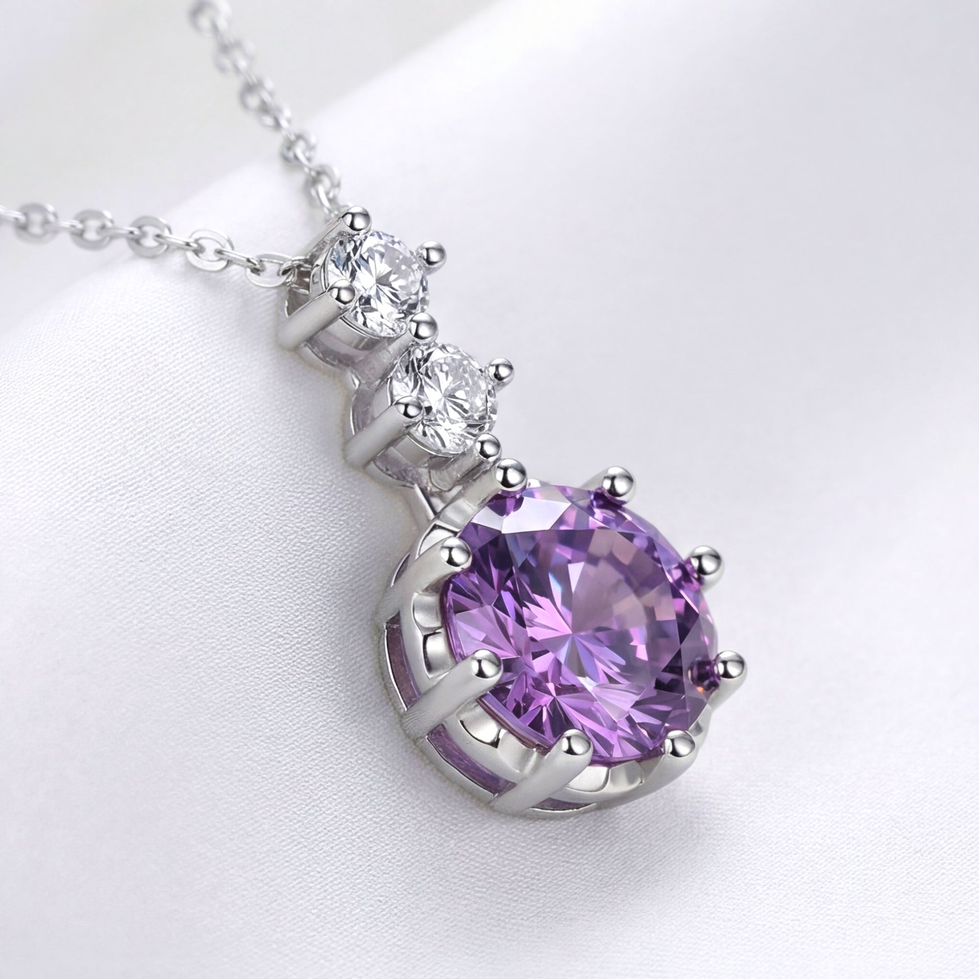 Round cut simulated amethyst pendant in S925 sterling silver on a white silk background.