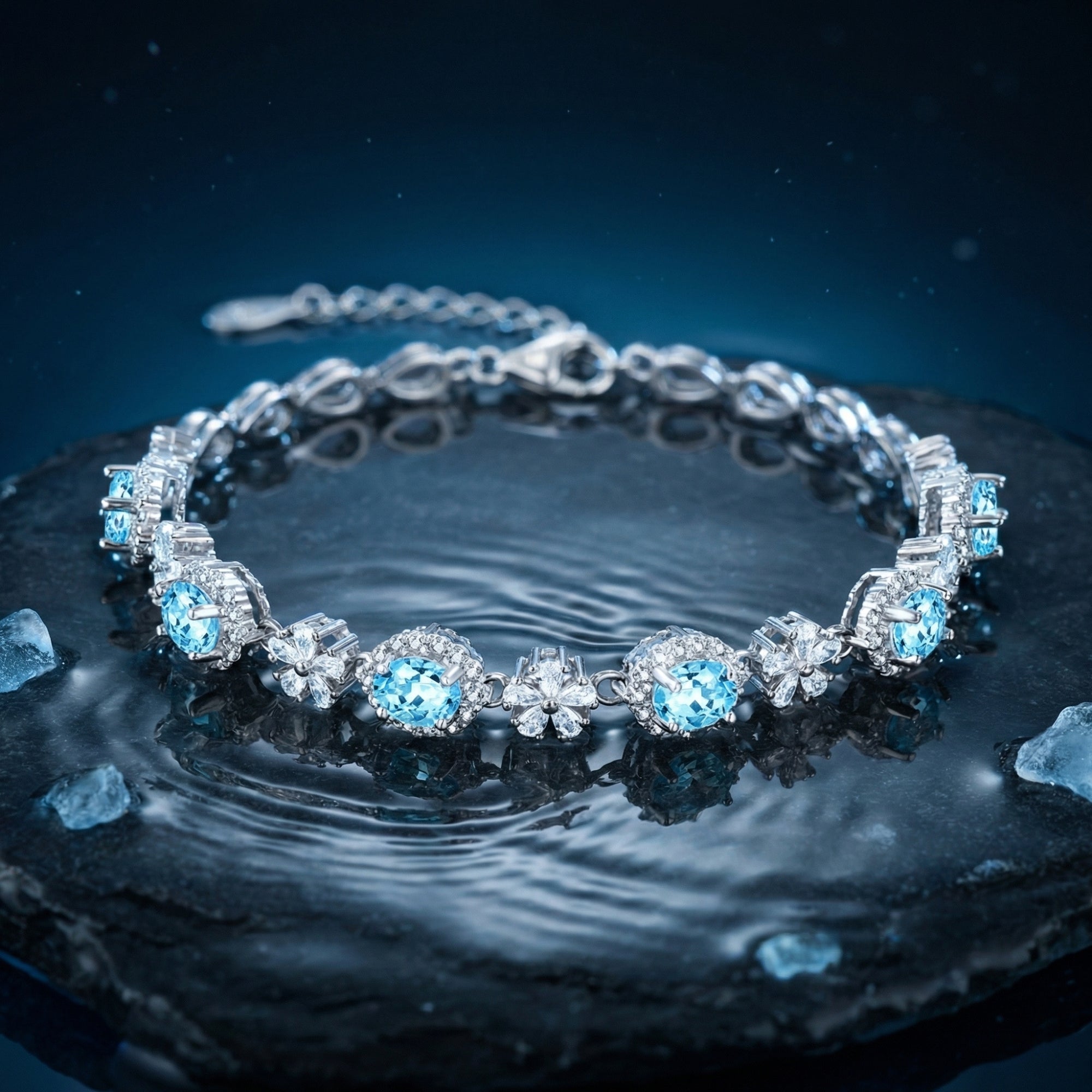 Natural aquamarine oval station bracelet in white gold on a dark stone surface with water ripples.