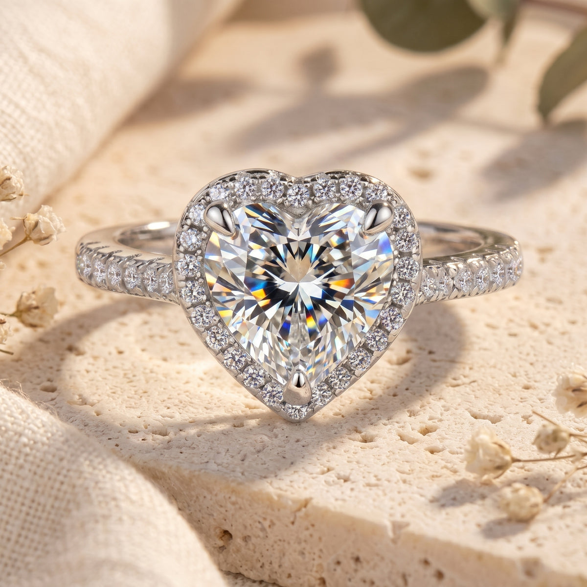 Front view of a silver heart-shaped halo ring with a simulated diamond and pavé band on a stone surface.