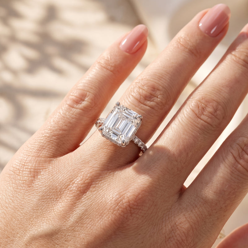 Top-down view of a hand wearing the silver emerald-cut solitaire ring with a sparkling pavé band.