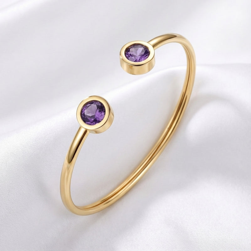 Gold stainless steel Liora open-cuff bracelet with round simulated amethyst stones on white silk.