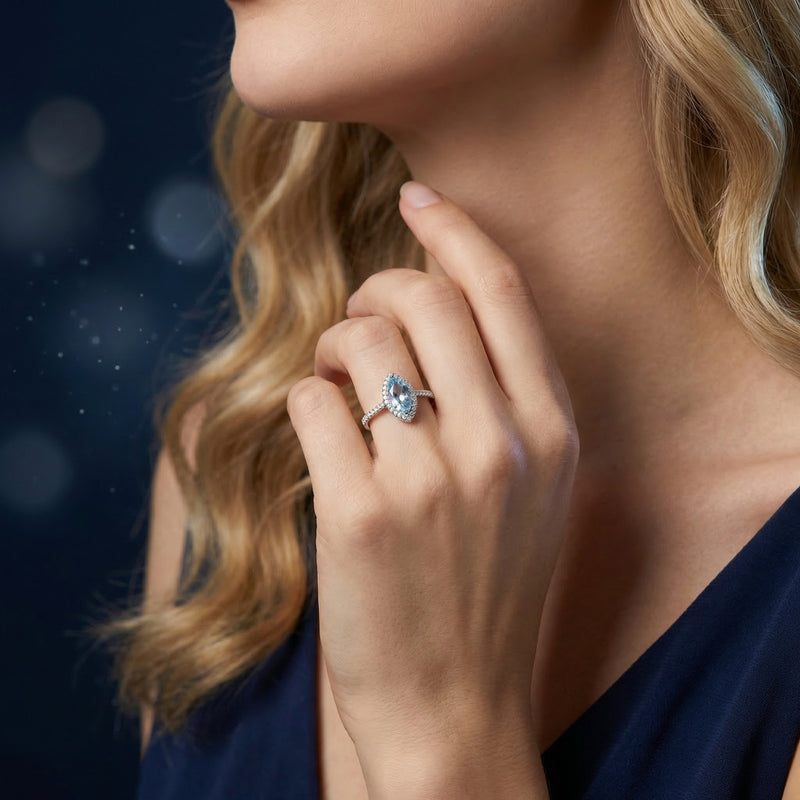 Model wearing the marquise cut natural blue topaz ring in sterling silver on her finger, paired with a navy dress.