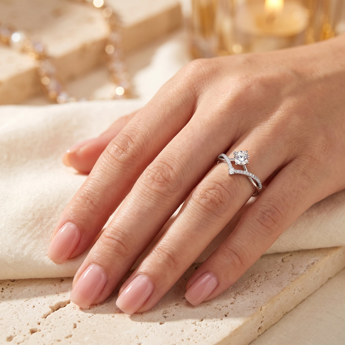 Silver chevron solitaire ring worn on a hand, displaying its wishbone pavé band and round center stone.