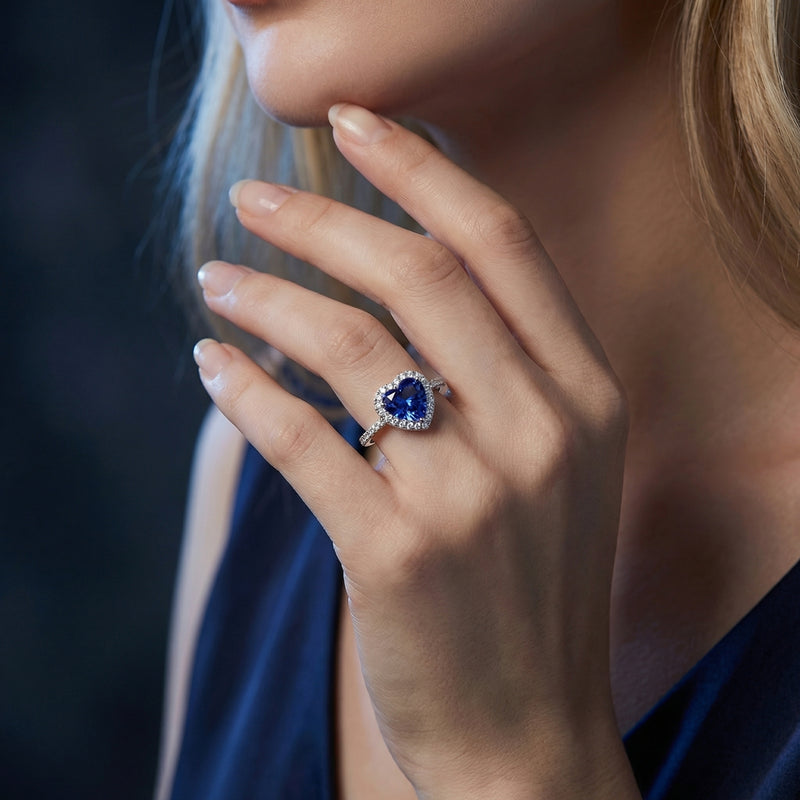 Heart-shaped tanzanite halo ring in sterling silver worn on a woman's hand.