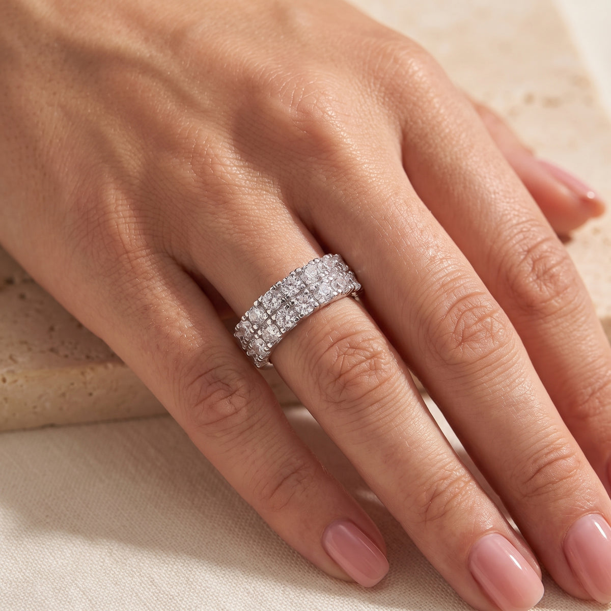 On-model view of the silver band ring with two rows of clear stones worn on a ring finger.