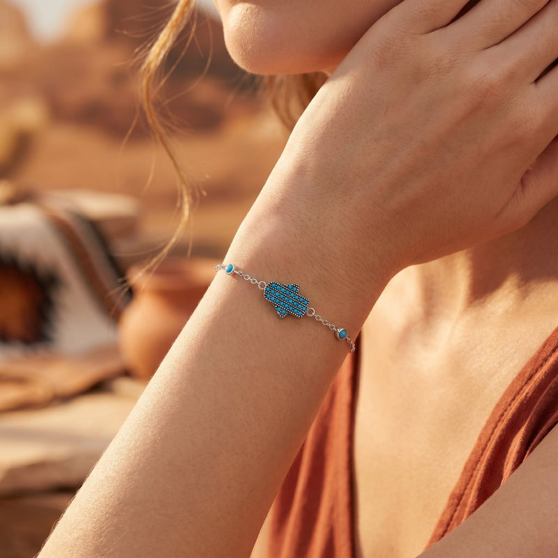 Woman wearing the silver Sedona turquoise Hamsa bracelet on her wrist in a desert landscape.