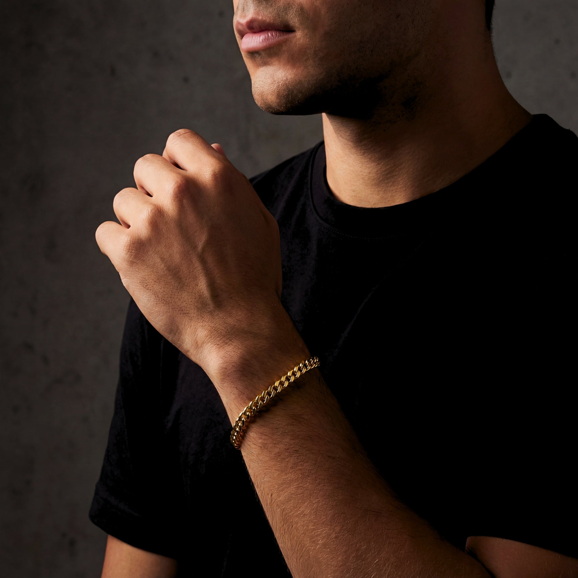 Man wearing the 8mm gold stainless steel Cuban link bracelet on his wrist with a black t-shirt.