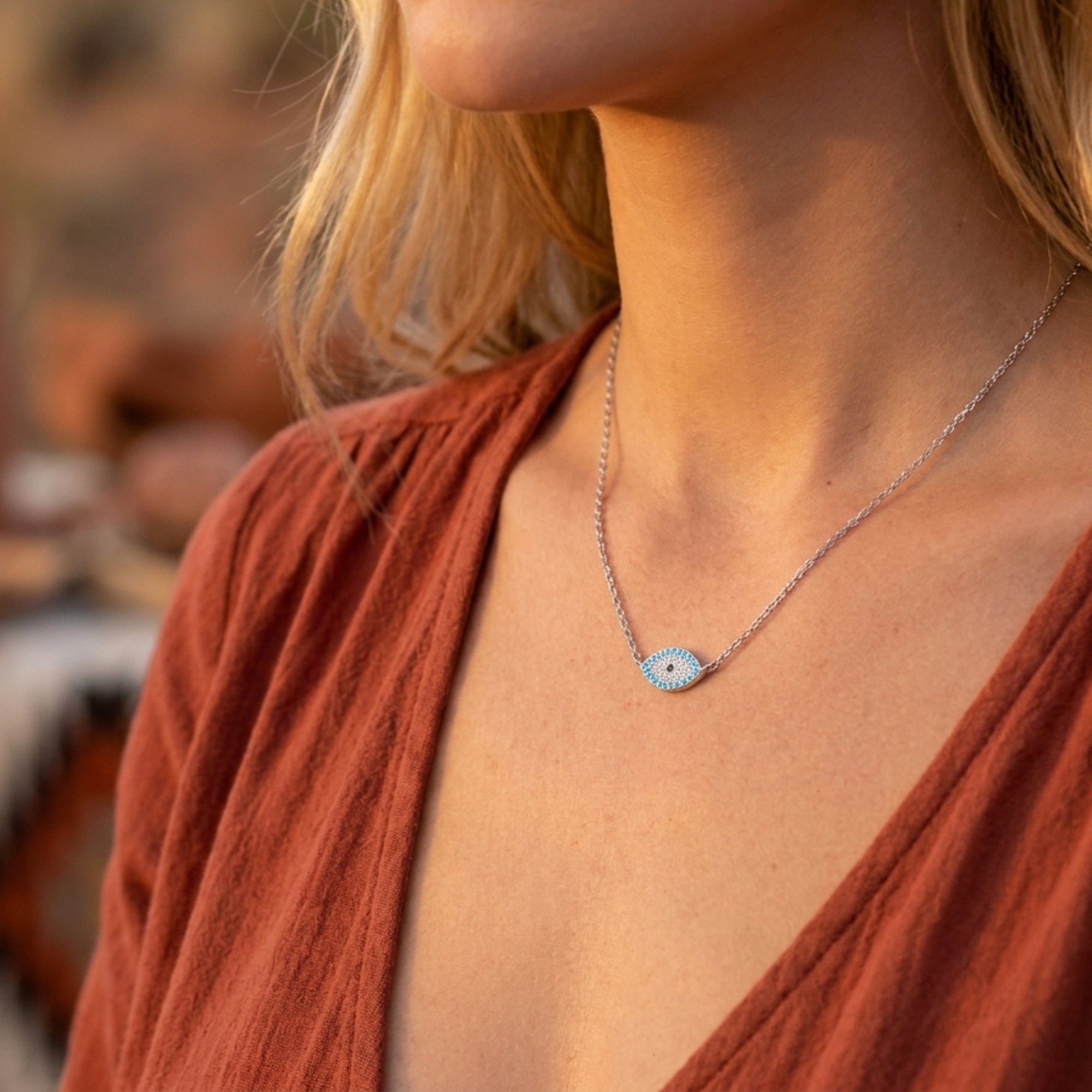 Model wearing the silver Aegean Turquoise eye necklace with a dainty chain and shimmering center stones.