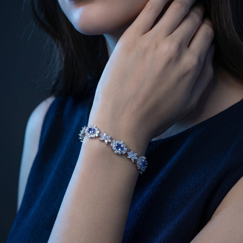 Model wearing the Rosalira floral tennis bracelet with blue tanzanite stones on her wrist.