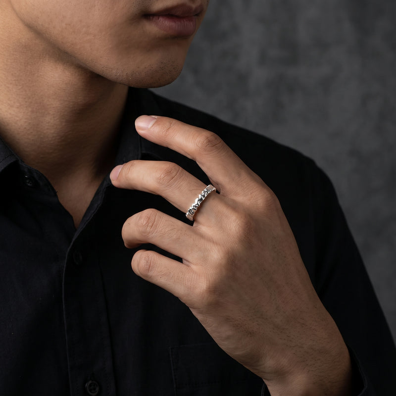 Silver carved open-band ring worn on a man's ring finger against a black shirt.