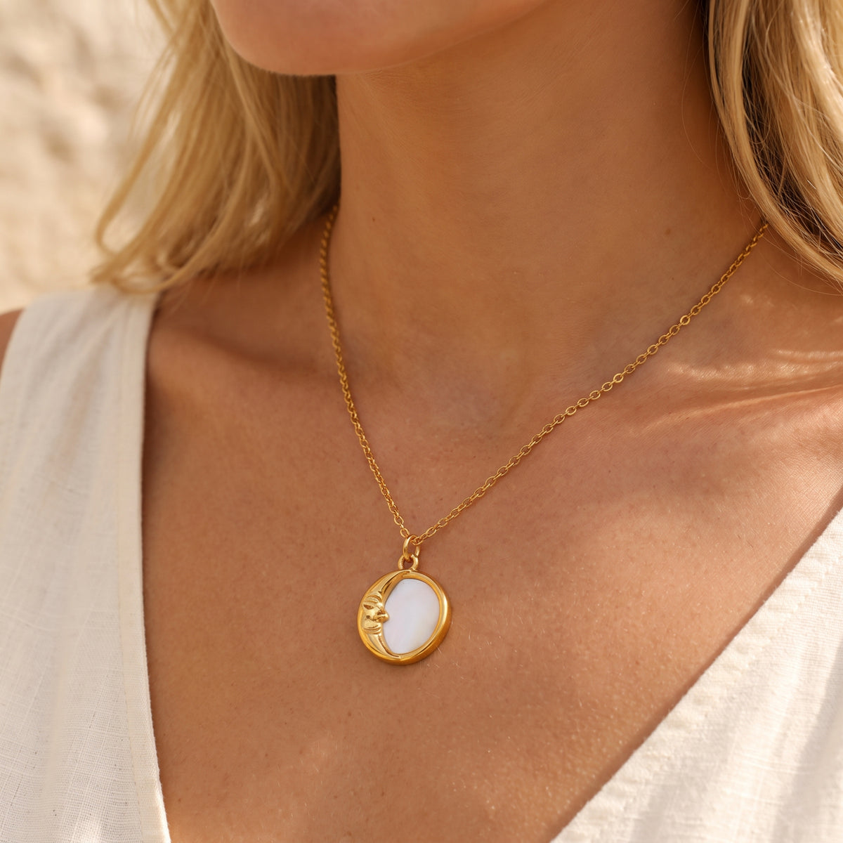 Model wearing the gold-tone crescent moon pendant necklace with a white sleeveless top.