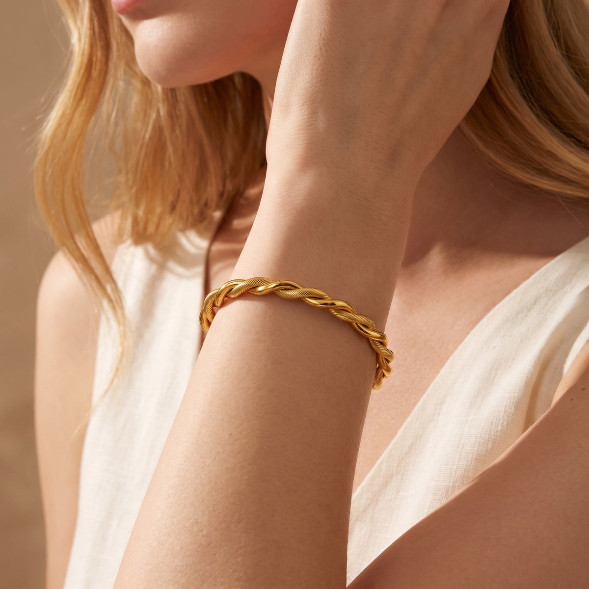 Side view of the gold-tone twisted cable cuff bracelet worn on a model's wrist.