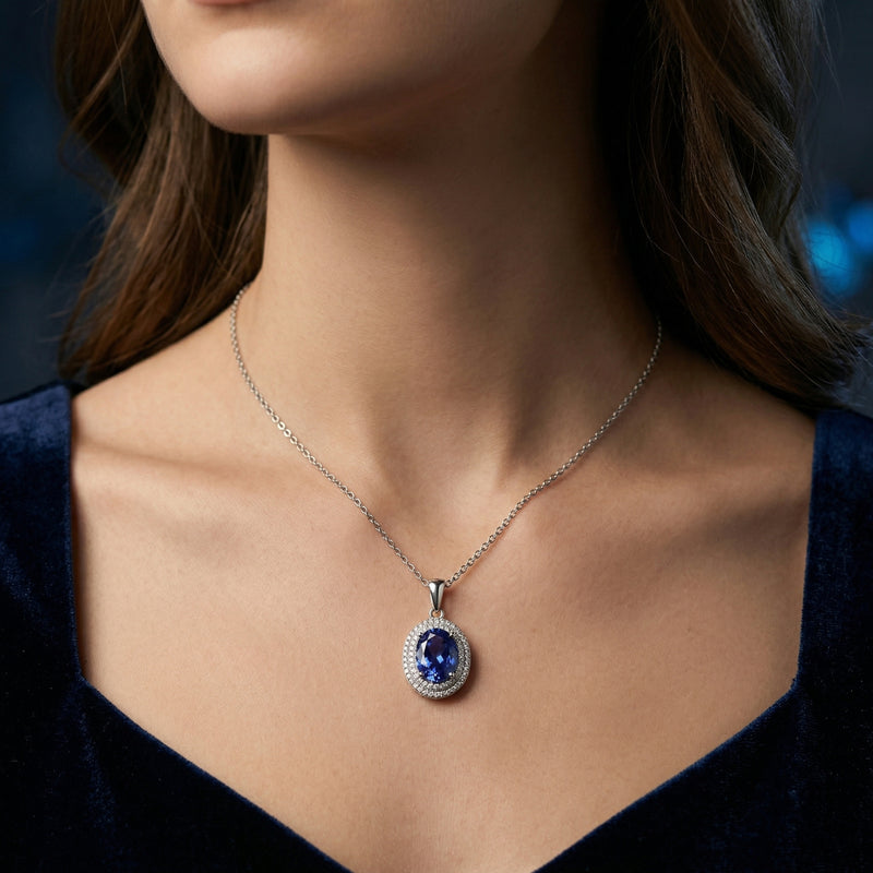 Model wearing the Oreliana oval tanzanite halo necklace in sterling silver with a dark blue dress.