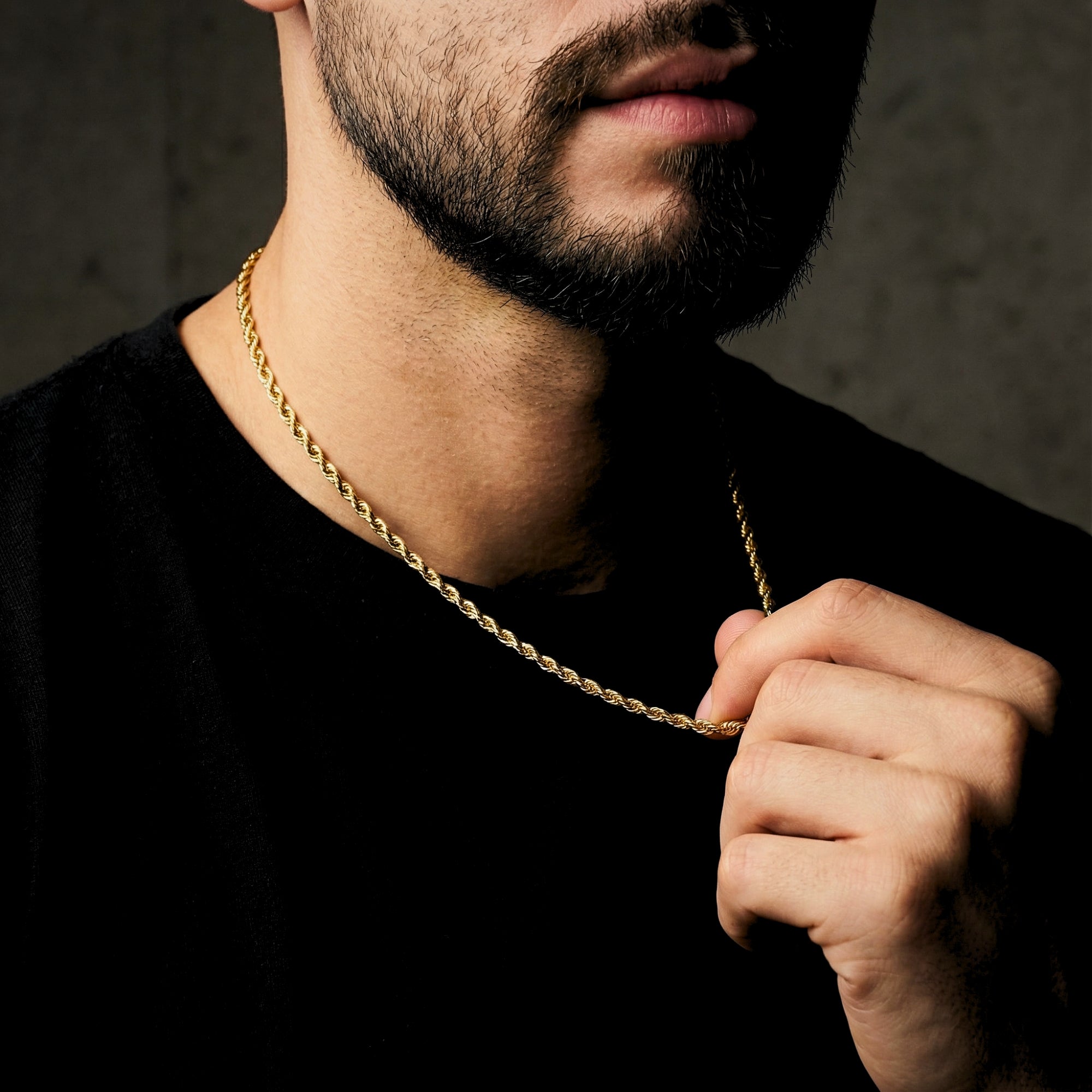 Close-up of a man wearing a 4mm gold stainless steel rope chain against a dark background.