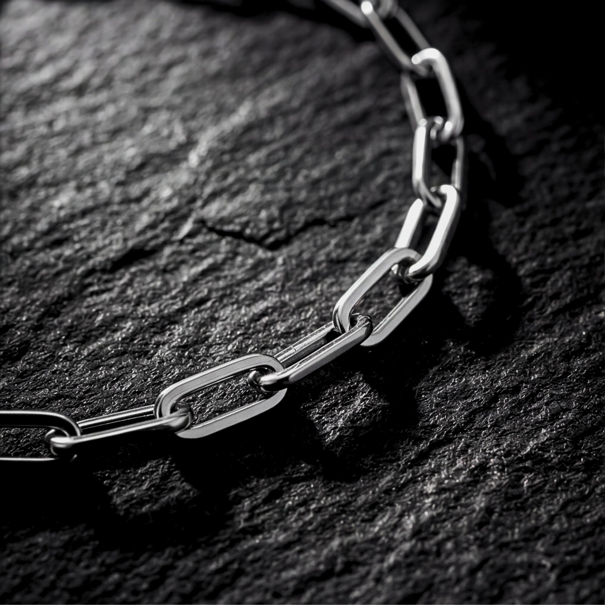Macro detail of the polished silver stainless steel links on a modern clip chain bracelet.