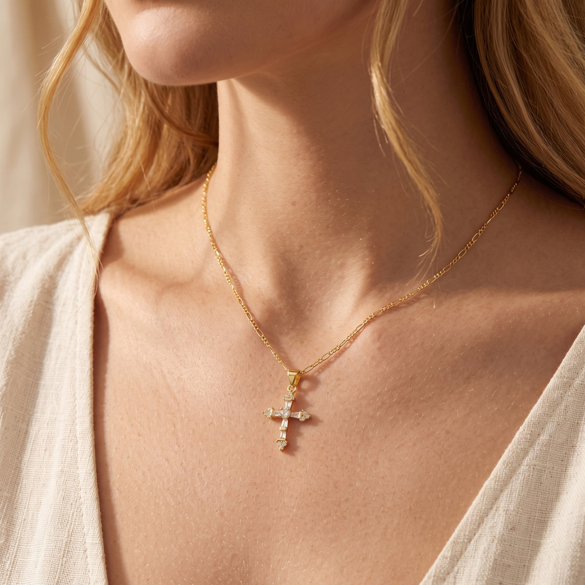 Model wearing the gold-tone cross pendant necklace over a light-colored open shirt.