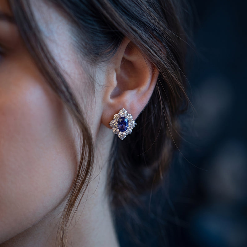 Close-up of a model wearing an oval natural tanzanite drop earring in white gold on her ear.