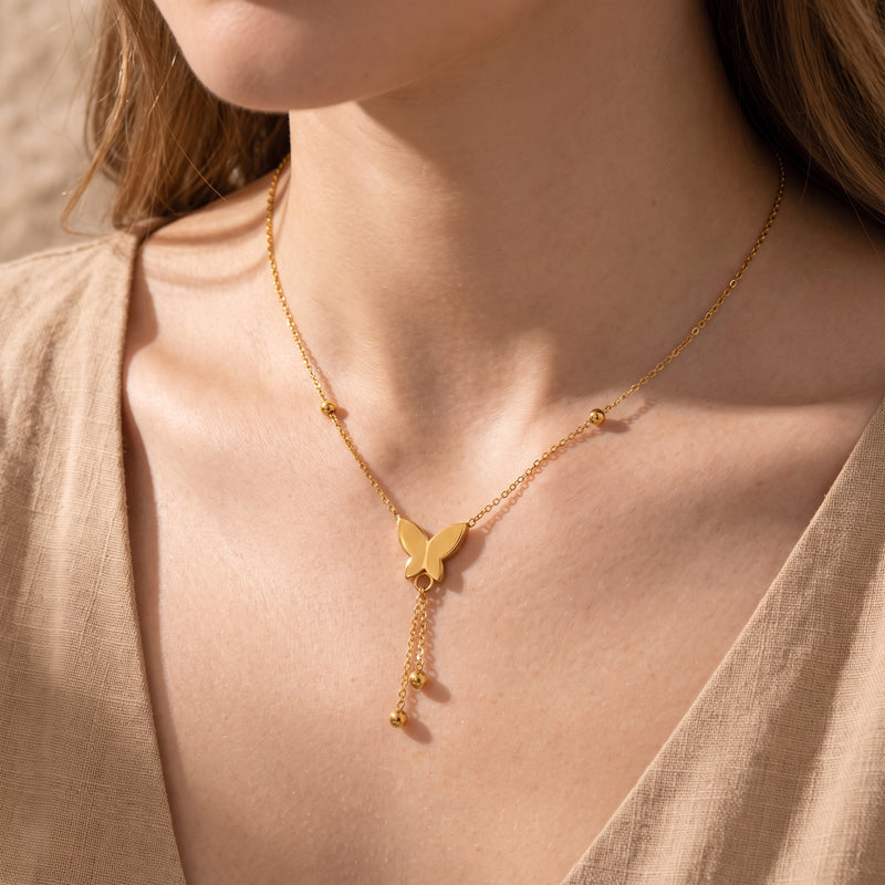 Close-up of a model wearing the gold-tone butterfly lariat necklace near her collarbone.