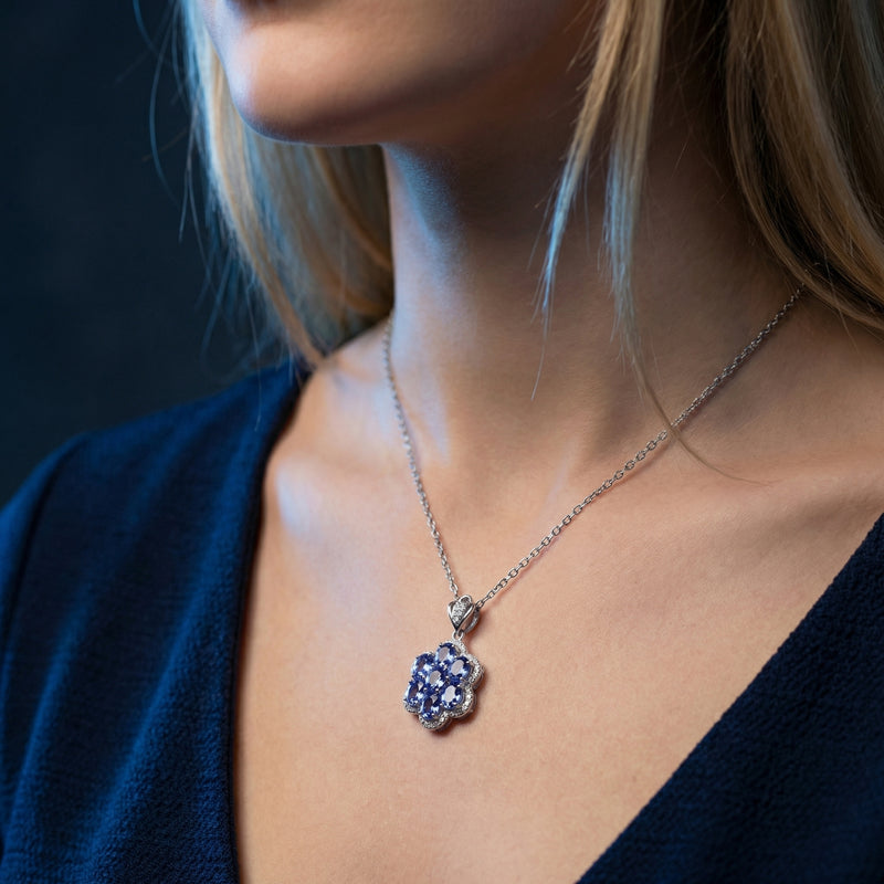 Model wearing the Caelestia floral cluster necklace with oval tanzanite stones in a white gold setting.
