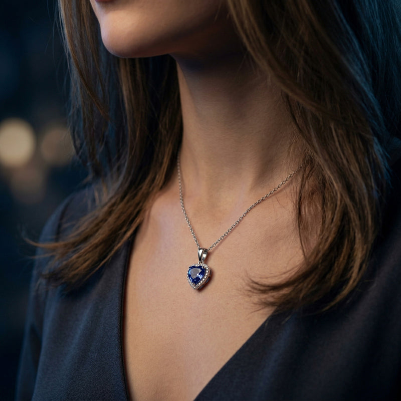 Model wearing the heart-cut tanzanite and zircon halo necklace in white gold on a delicate silver chain.