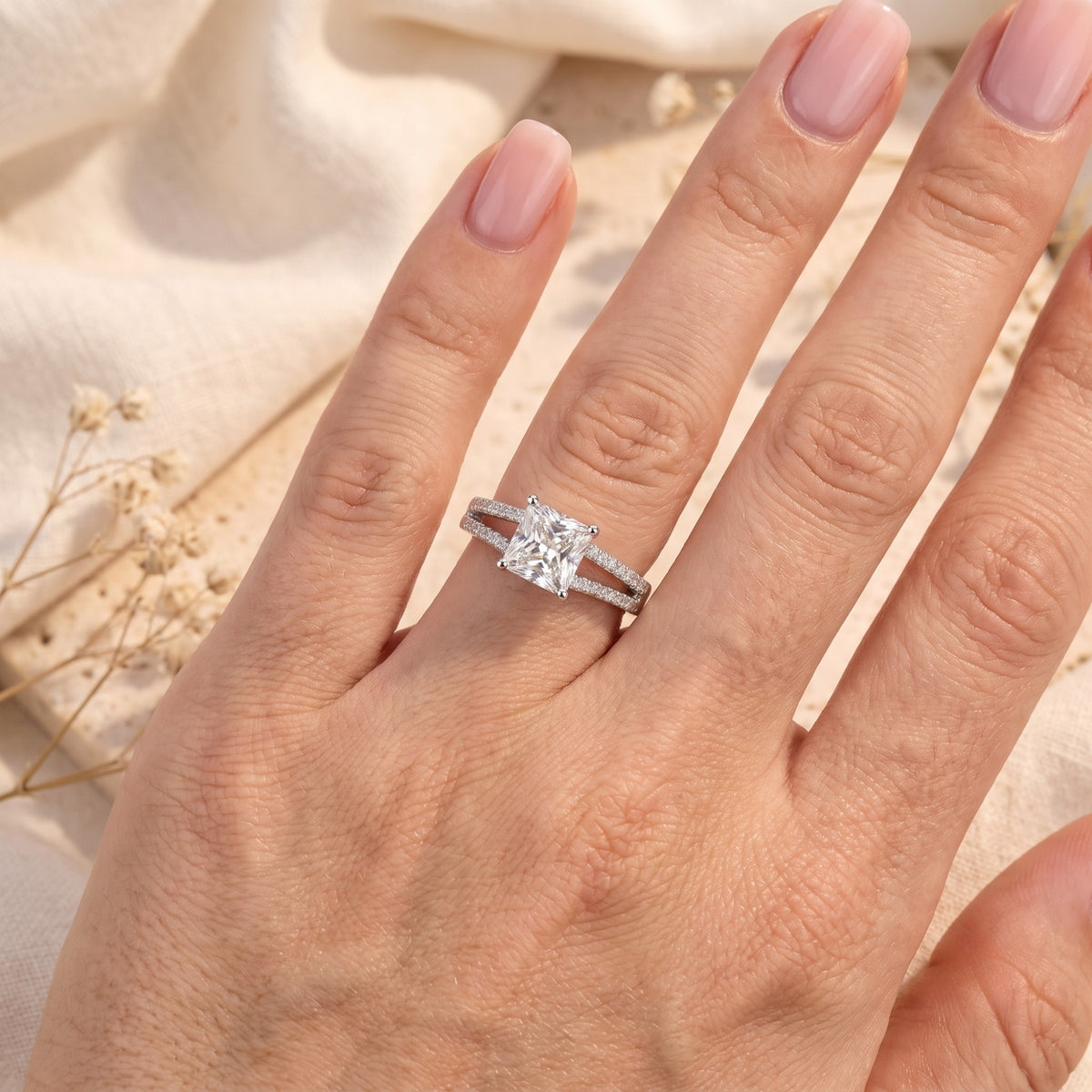 Silver split-shank solitaire ring with a square princess-cut stone shown on a hand.