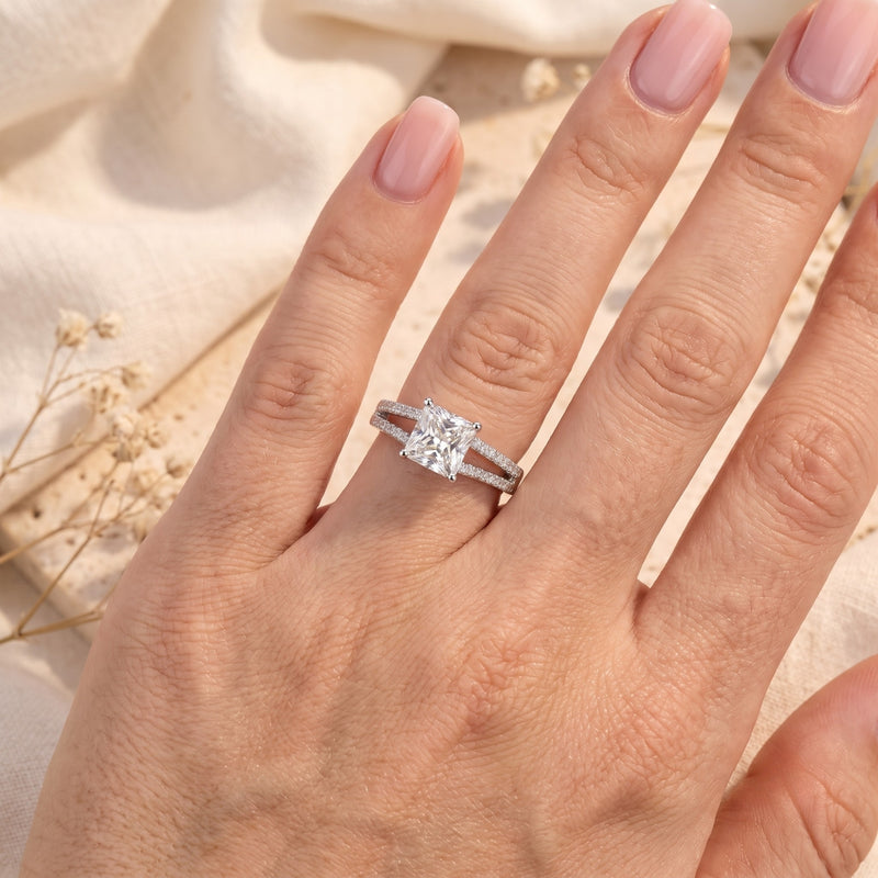 Silver split-shank solitaire ring with a square princess-cut stone shown on a hand.