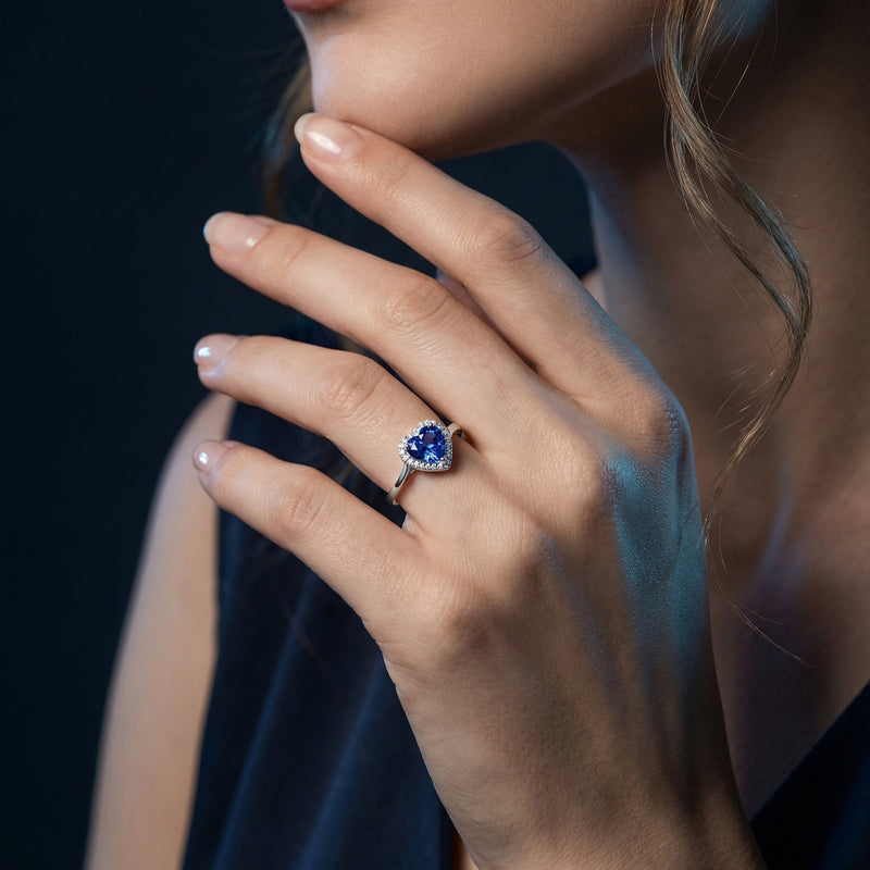 Model wearing the heart-shaped tanzanite ring in sterling silver on her finger, showing scale and elegance.