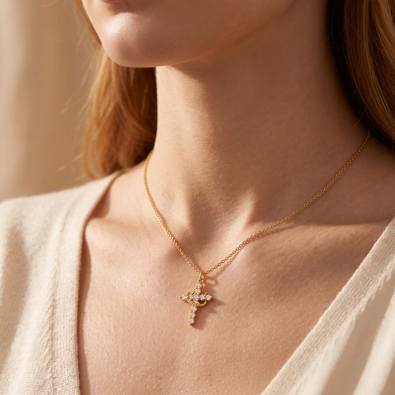 Close-up of a model wearing the gold-tone crown cross necklace against a light beige sweater.