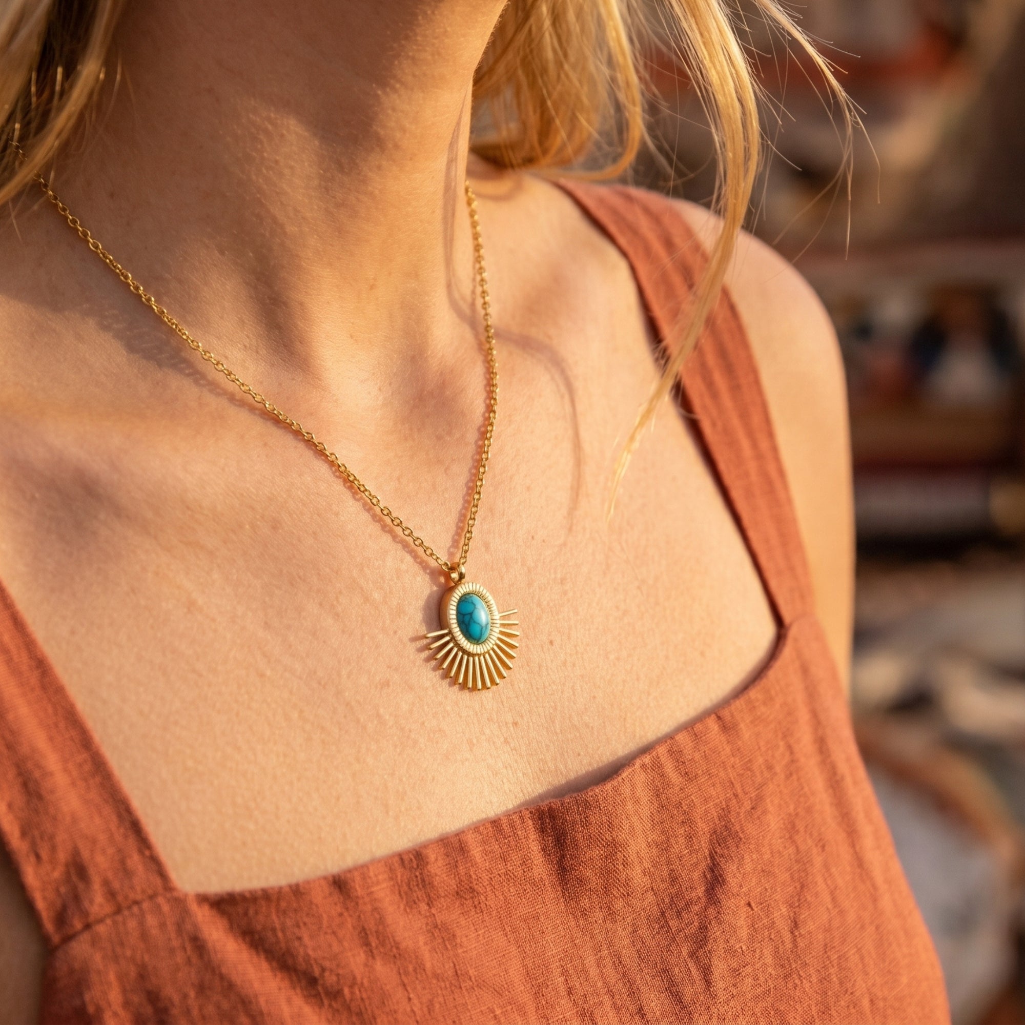 Gold sunburst turquoise pendant necklace worn by a model in a terracotta linen top for a Southwestern look.