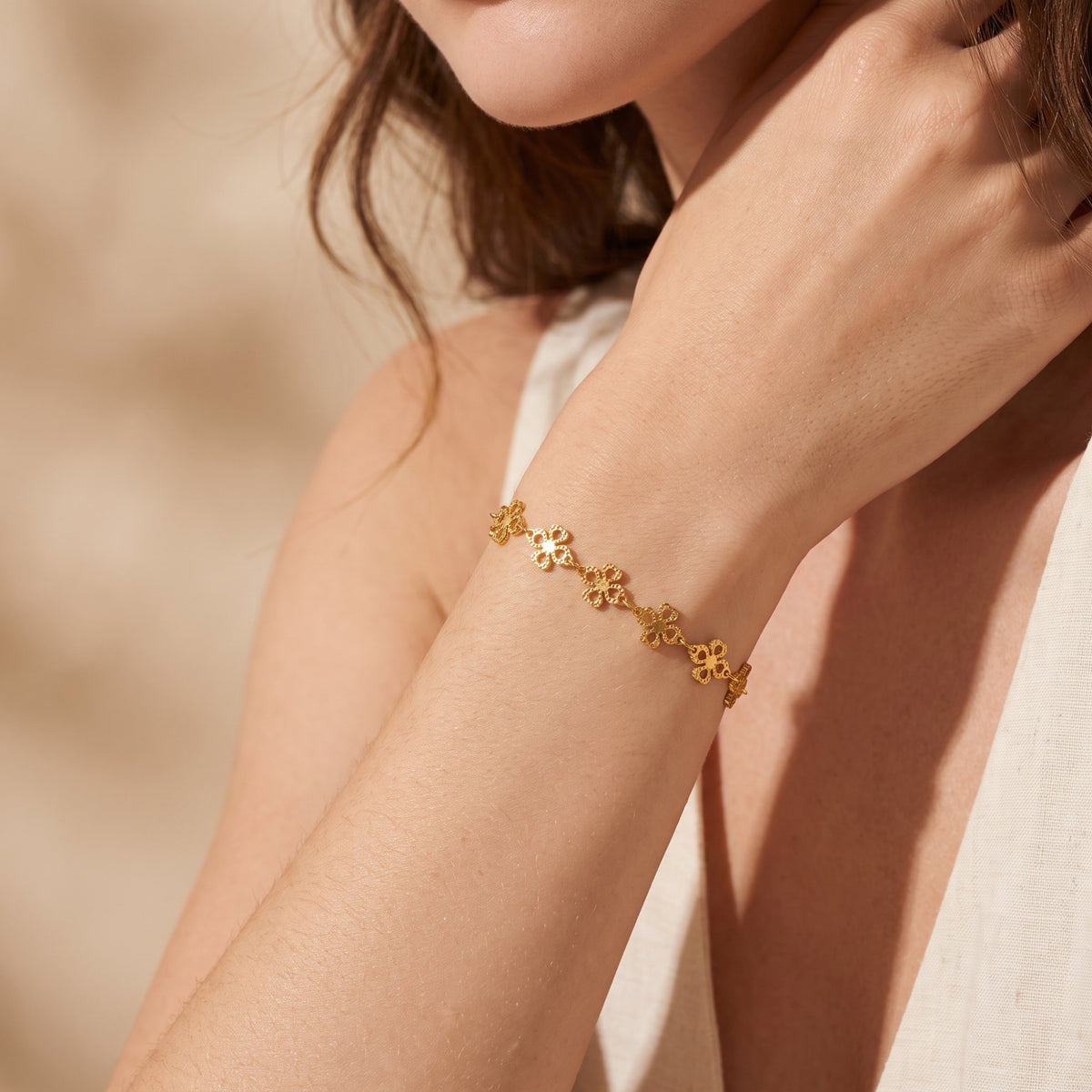 Close-up of a model wearing the gold-tone four-leaf clover station bracelet on her wrist.