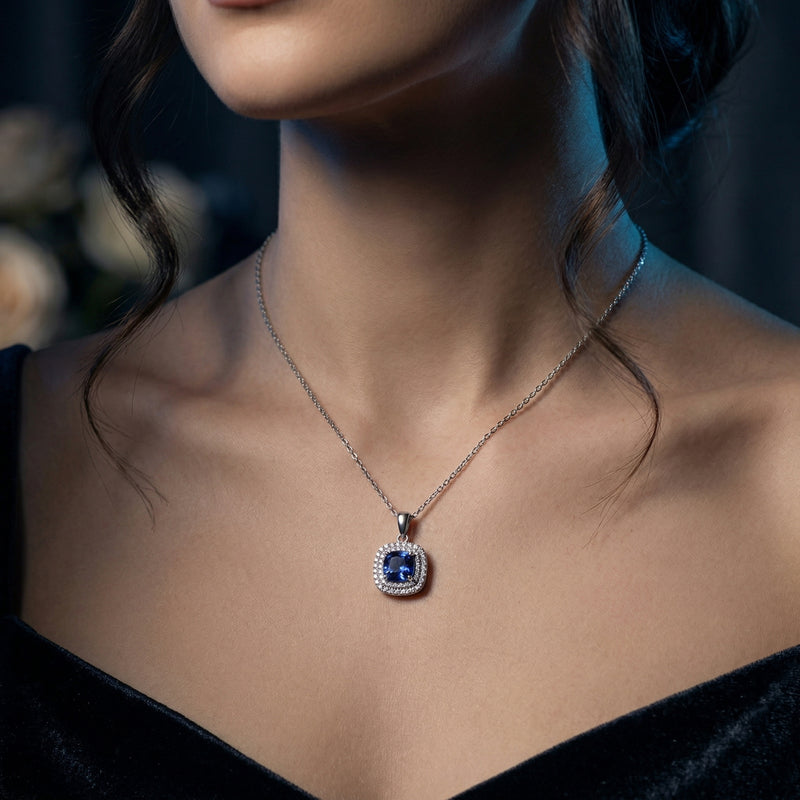 The Kaelis tanzanite necklace in sterling silver with a cushion cut blue gemstone worn by a model.