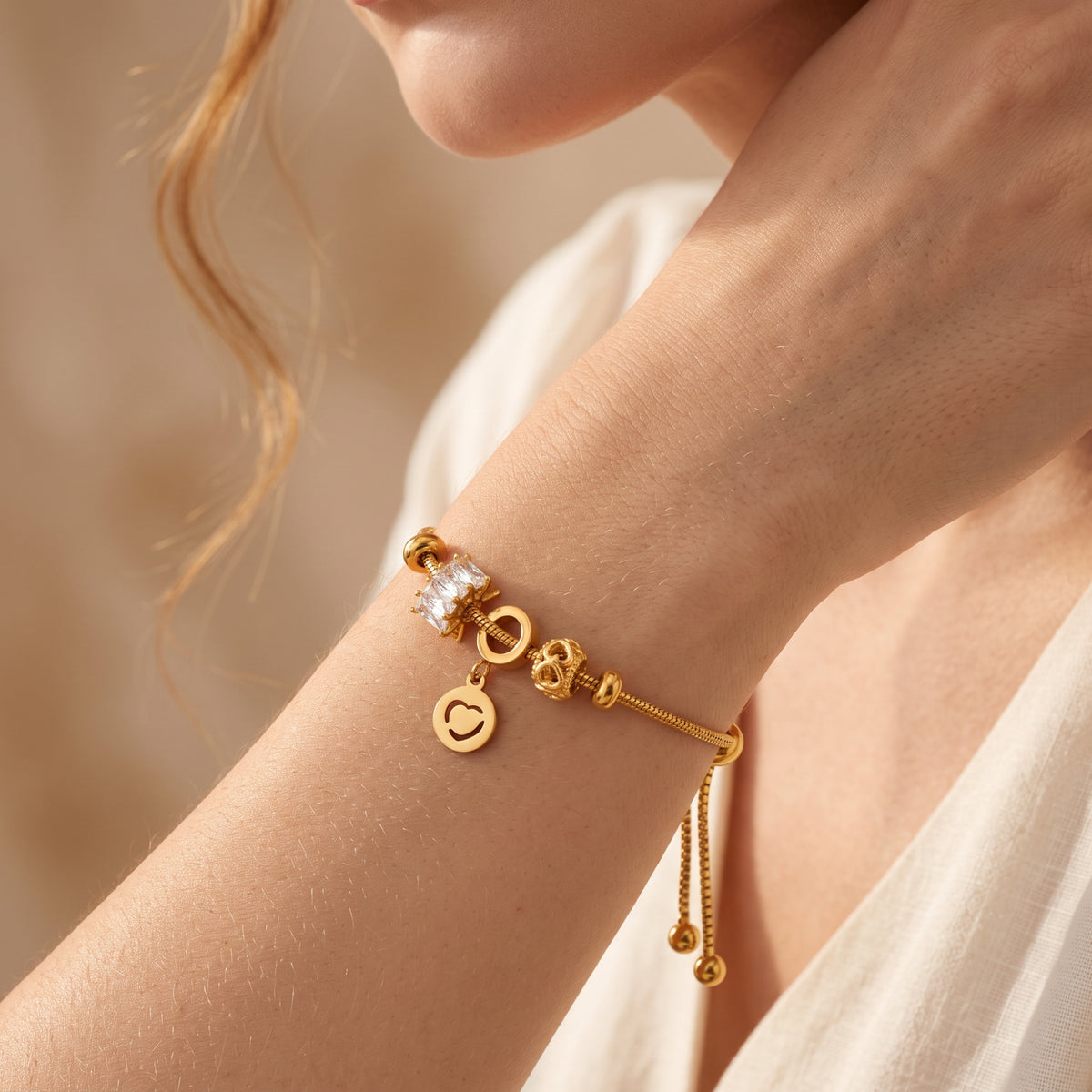 Gold-tone heart charm bracelet worn on a wrist, with a hanging heart charm and crystal accent visible.