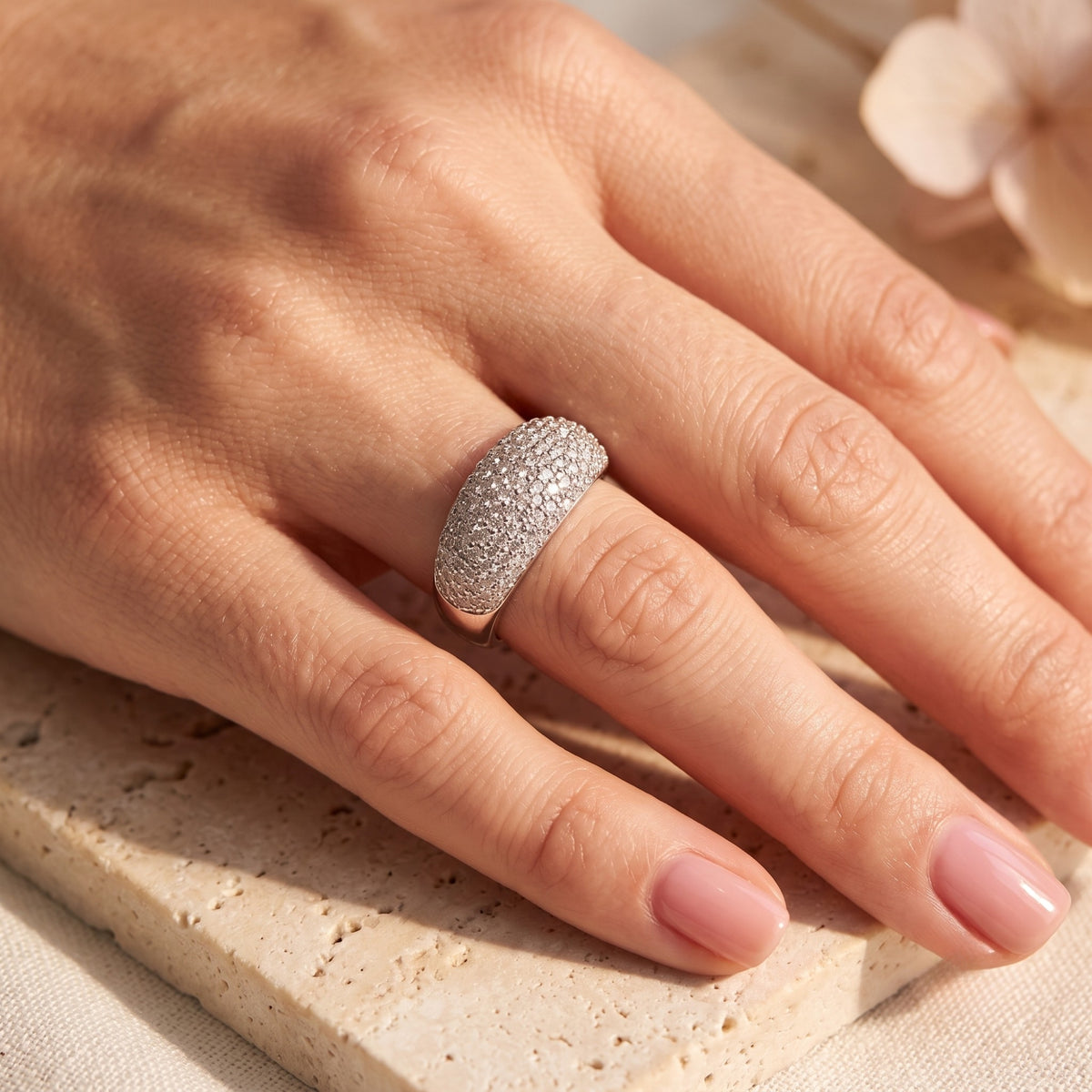 Solid white gold pave dome ring worn on a hand, showing shimmering cubic zirconia stones.