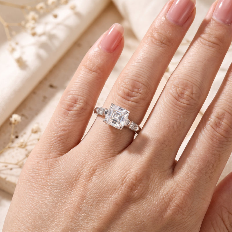On-hand view of the silver ring with a square radiant-cut central stone worn on a ring finger.