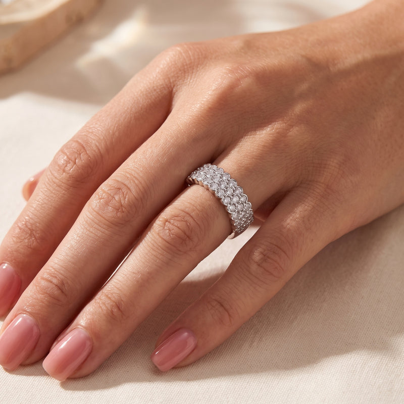 Close angled view of a hand wearing the silver scalloped triple-row clear-stone ring on the ring finger.