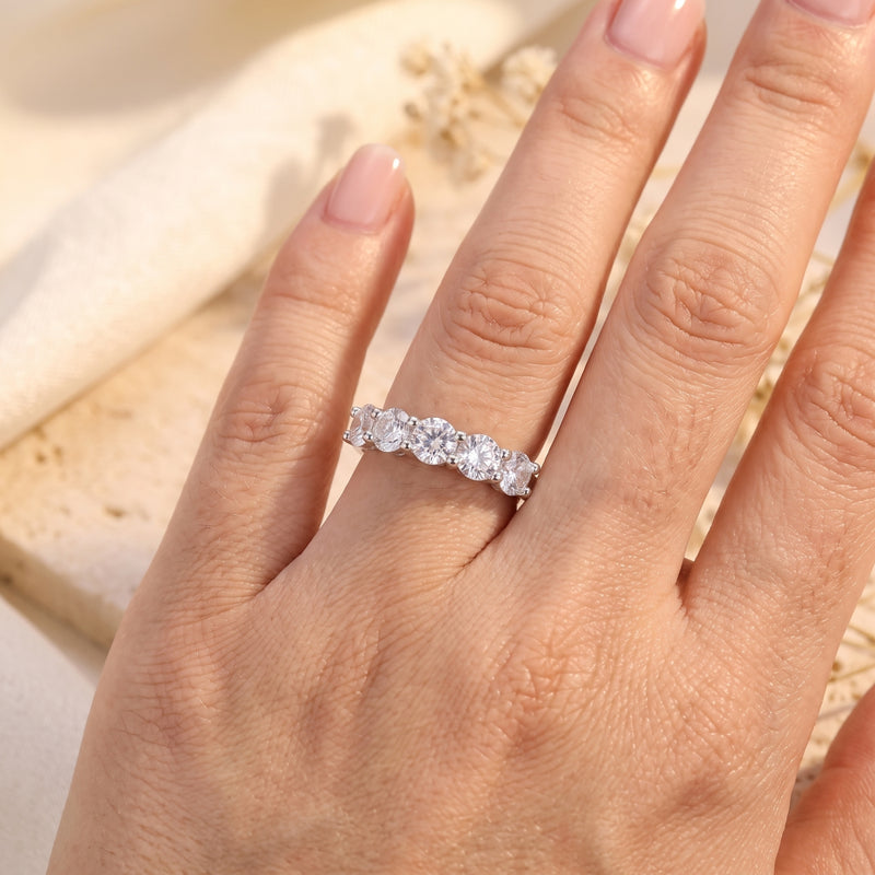 Direct view of the silver five-stone band ring with round clear stones worn on a hand.